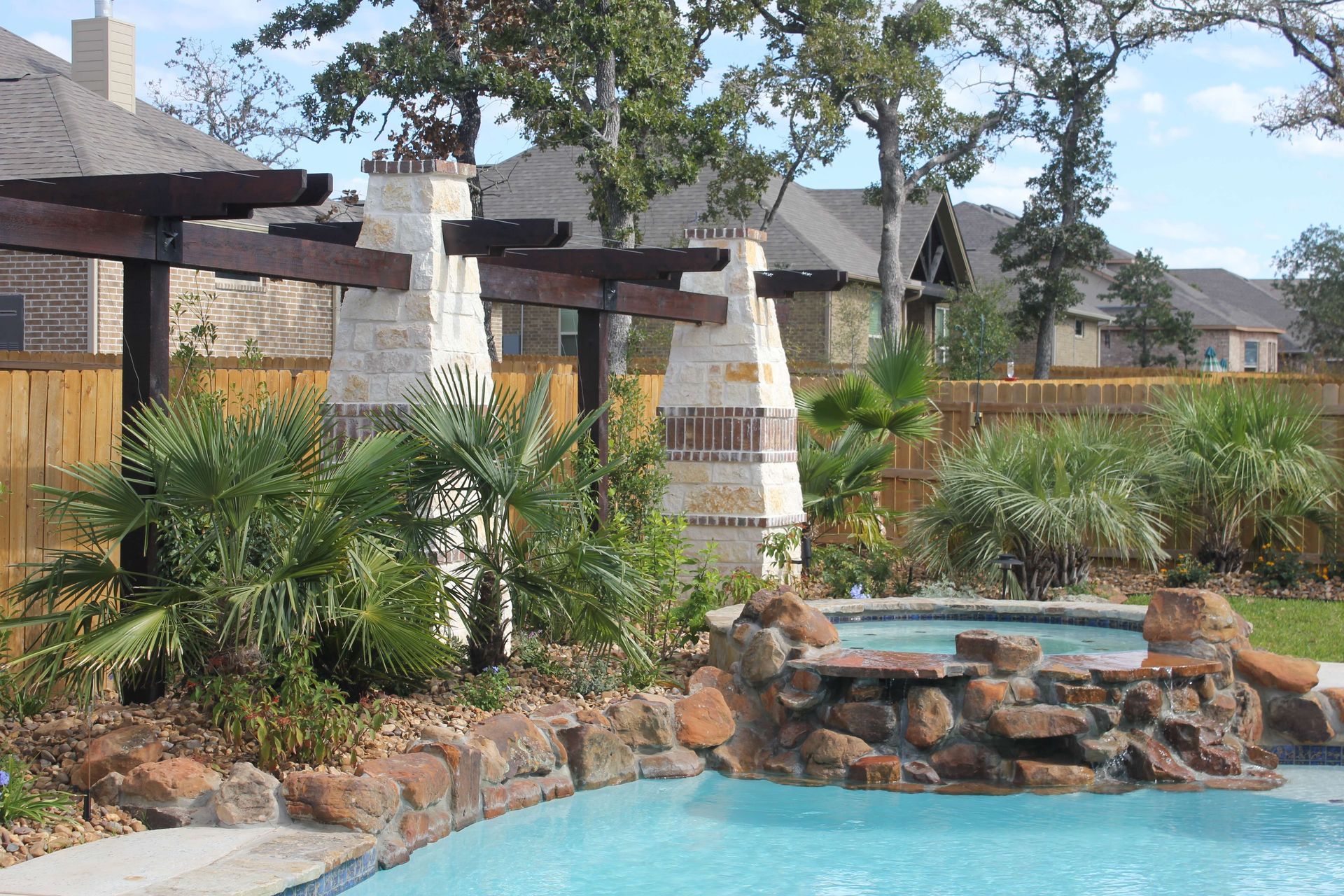 A swimming pool with a fireplace and a waterfall in the backyard