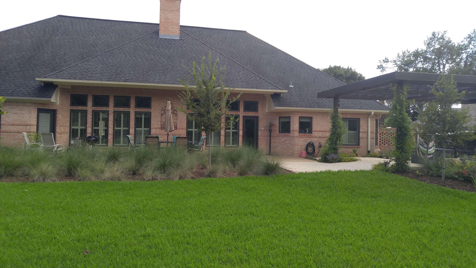 A large brick house with a large lawn in front of it.