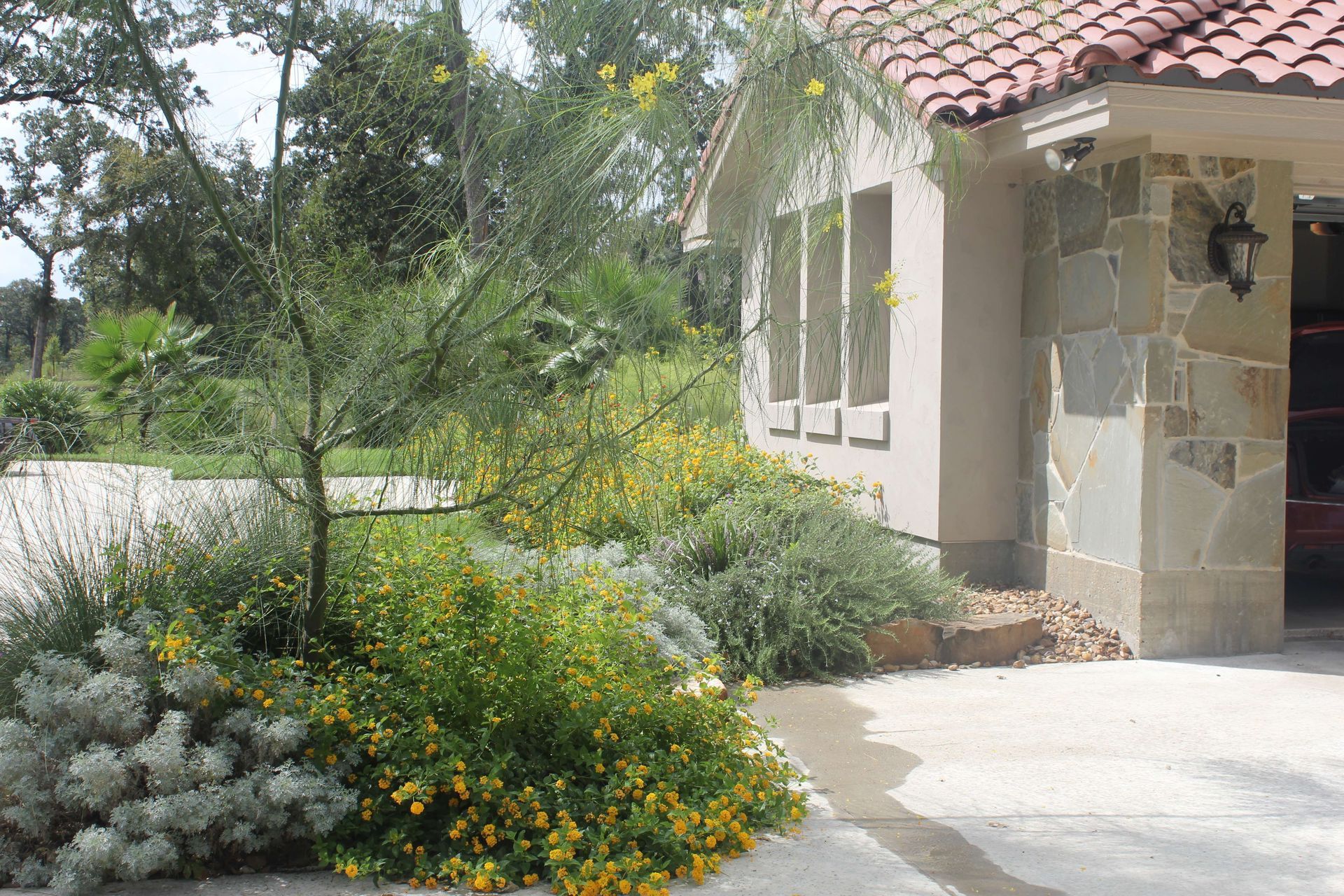 A house with a red tile roof and flowers in front of it