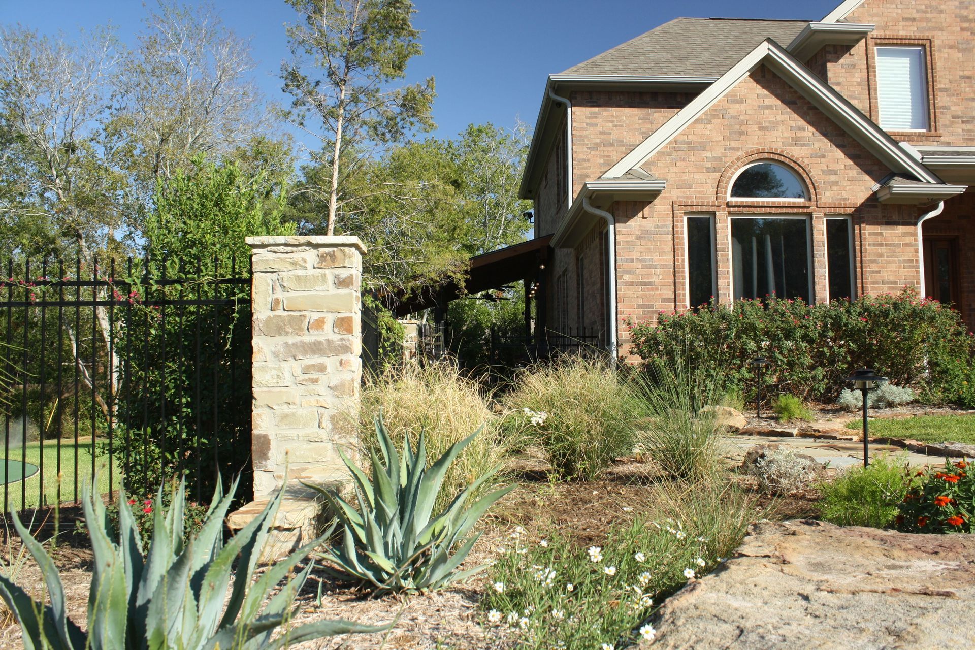 A large brick house with a fence and a stone pillar in front of it