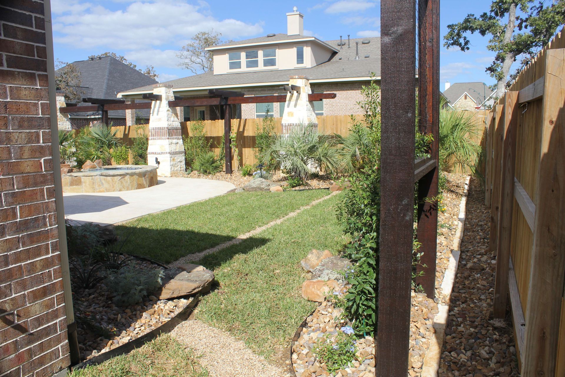 A backyard with a fence and a house in the background