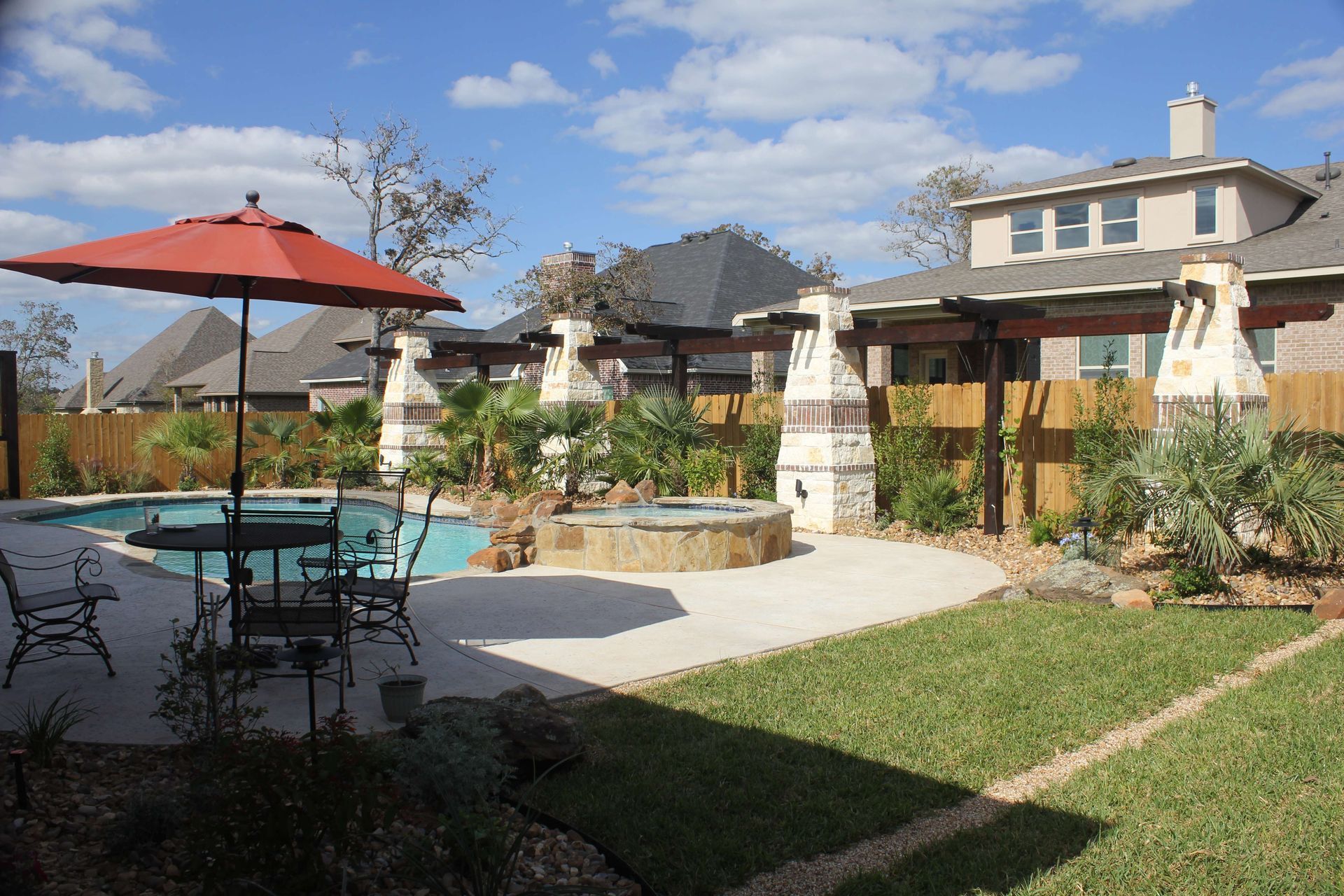 A backyard with a swimming pool and a red umbrella