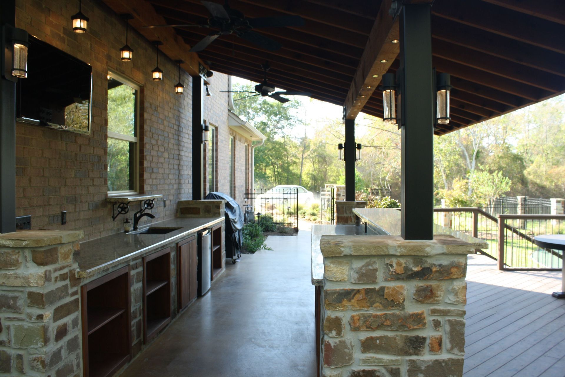 A large outdoor kitchen with a brick wall and a ceiling fan