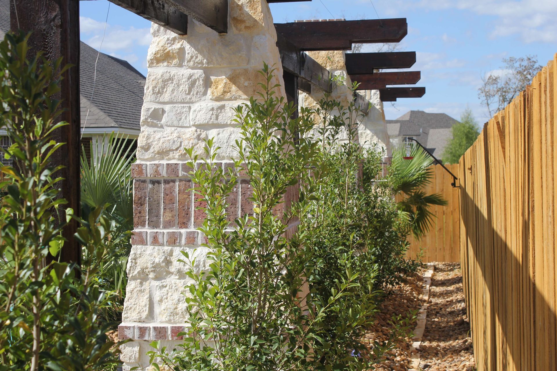 A brick wall with a wooden pergola and a wooden fence
