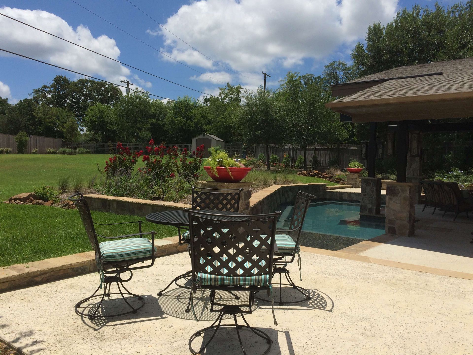 A table and chairs on a patio next to a pool.