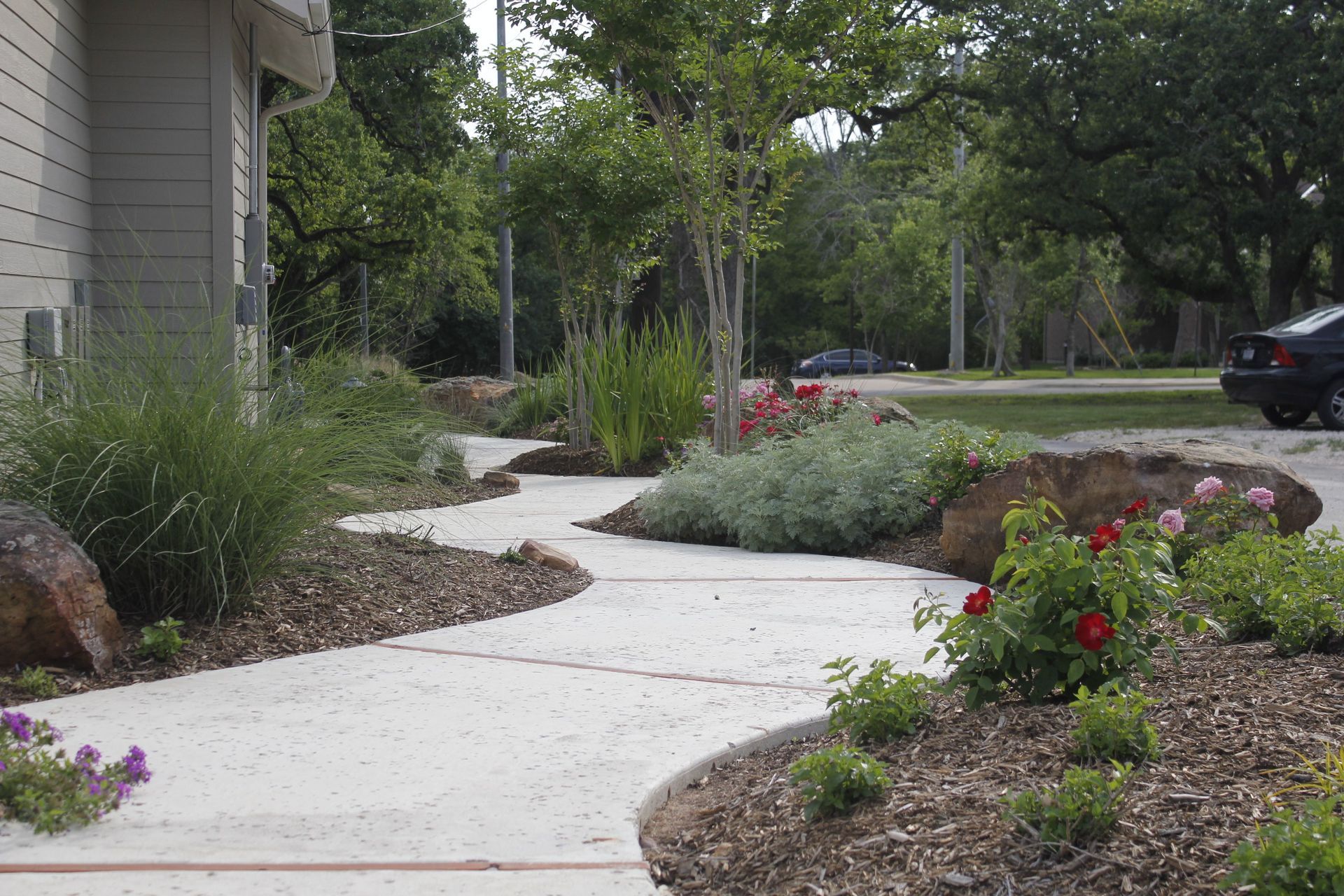 A sidewalk leading to a house with a car parked on the side of it