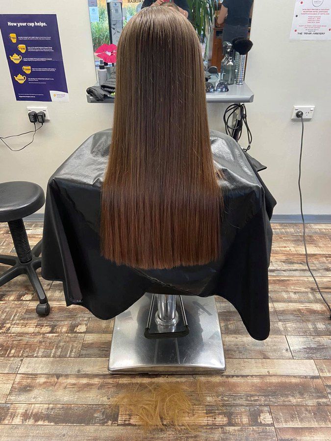 Hairdresser Straightening Long Brown Hair — Hair Salon In Dubbo, NSW