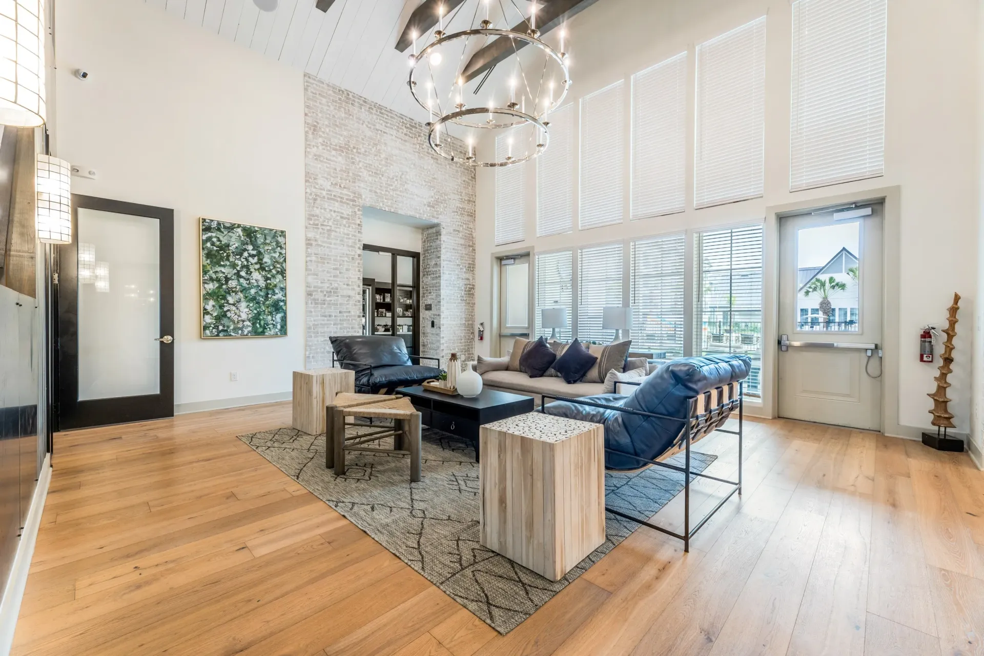 Modern leasing office lounge area with comfortable seating, coffee table, and large windows.