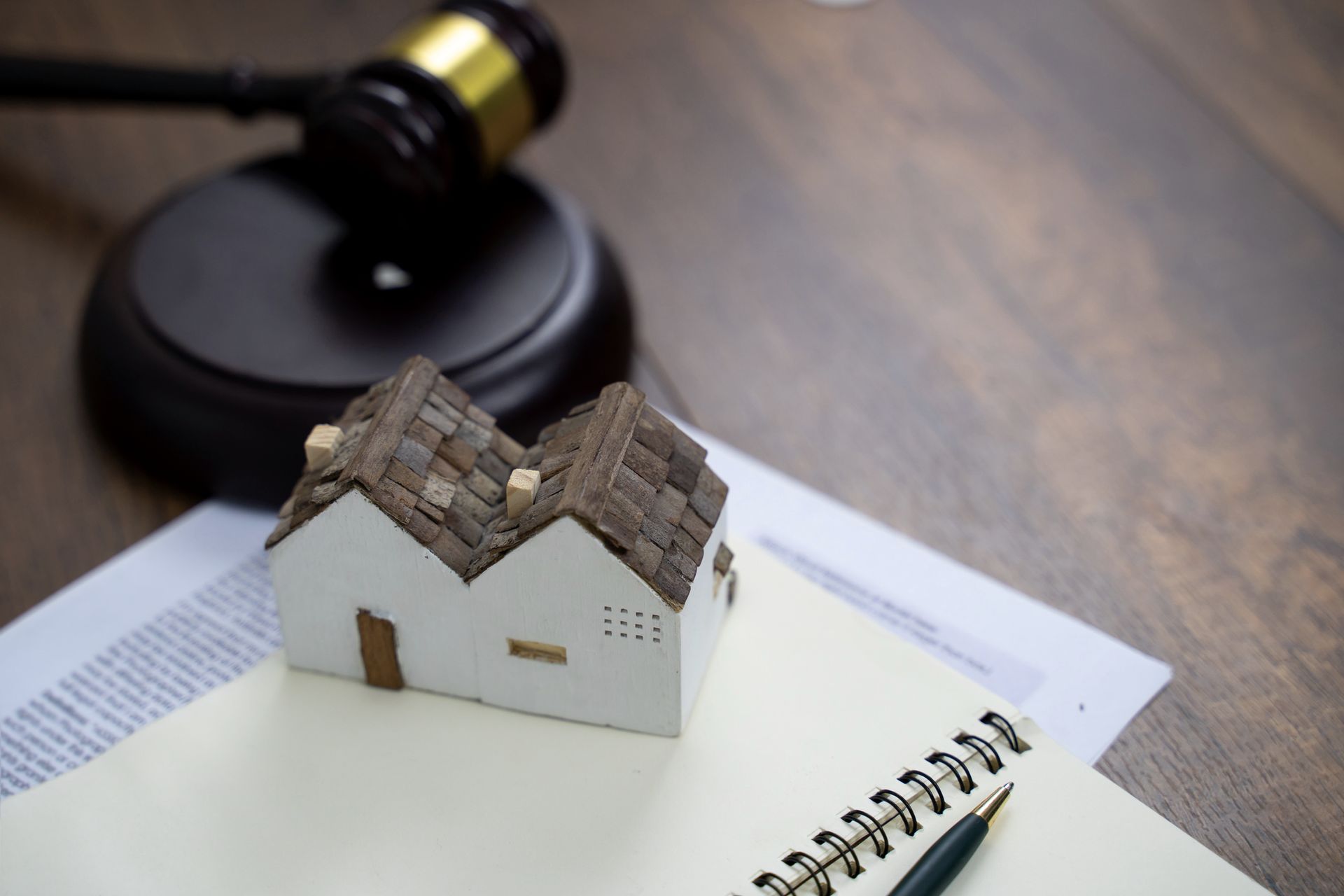 A gavel next to a small house model symbolizes legal aspects of estate planning and property.