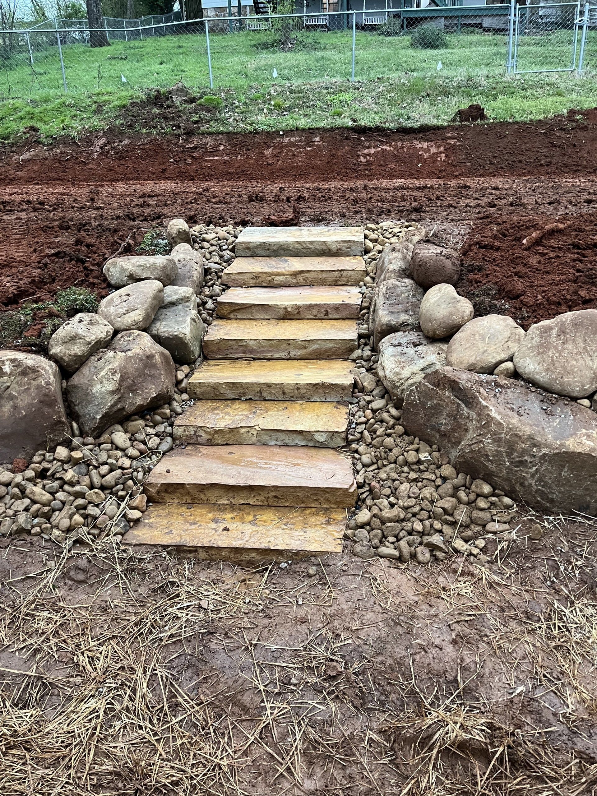 A stone walkway surrounded by rocks in a yard.