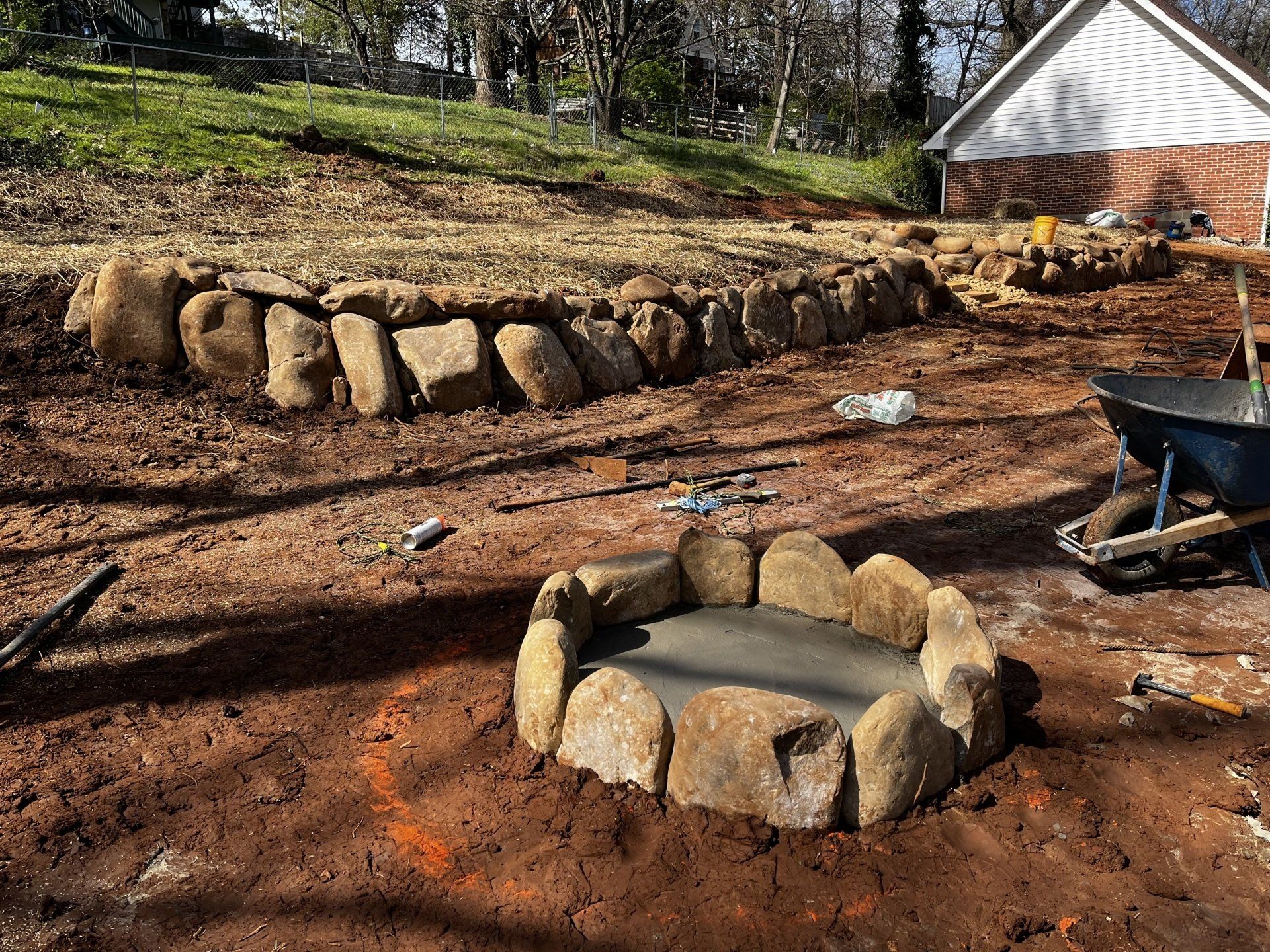 A fire pit is being built in the dirt in front of a house.