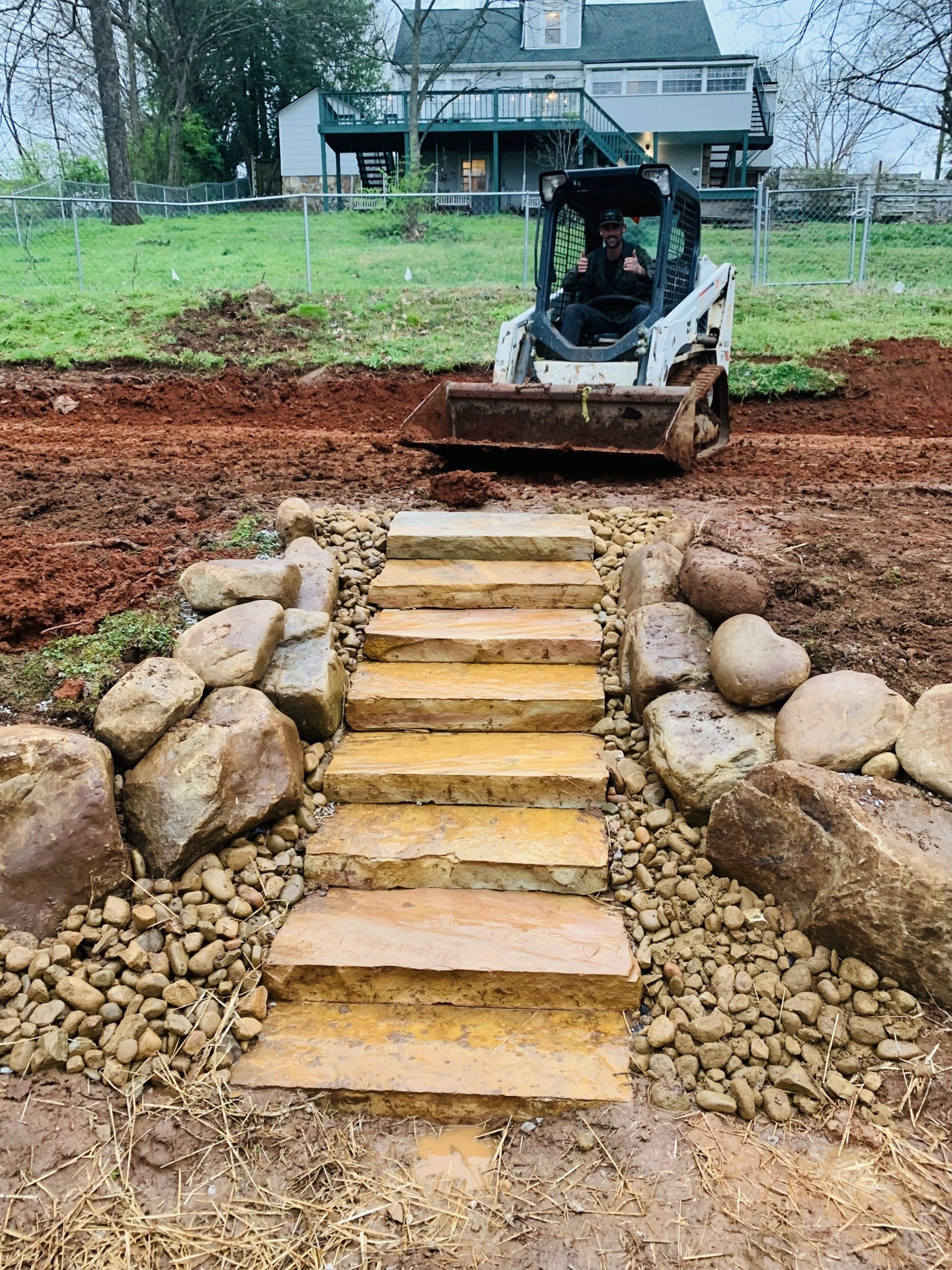 A bulldozer is driving down a path with stairs and rocks.