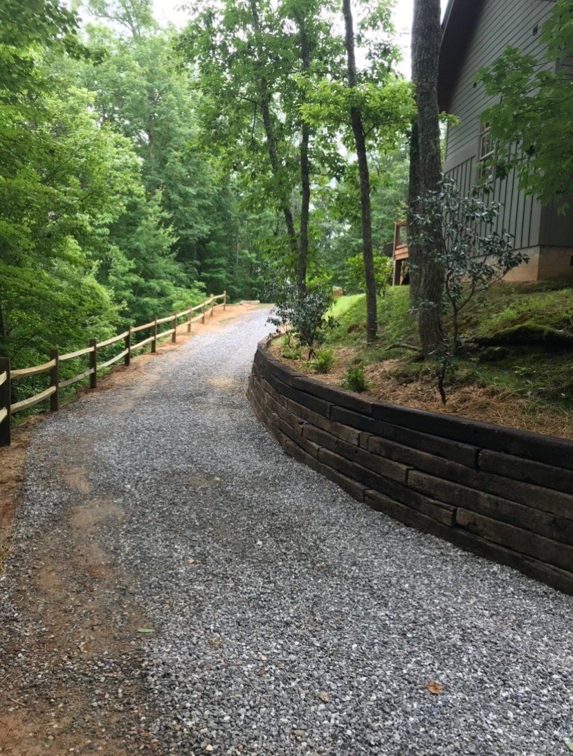 A gravel driveway leading to a house in the woods.