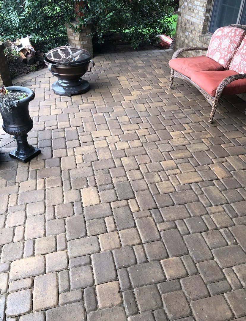 A patio with a couch , chairs , vases and a fire pit.
