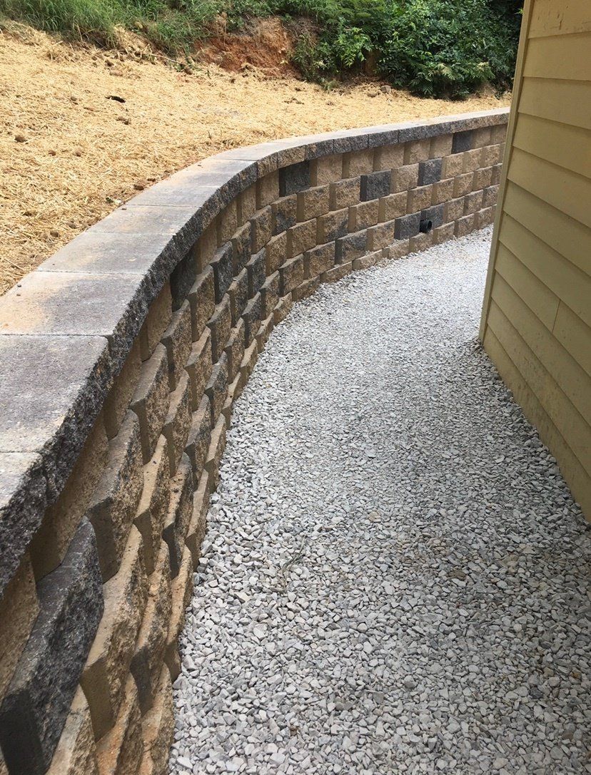 A brick wall is surrounded by gravel next to a house.