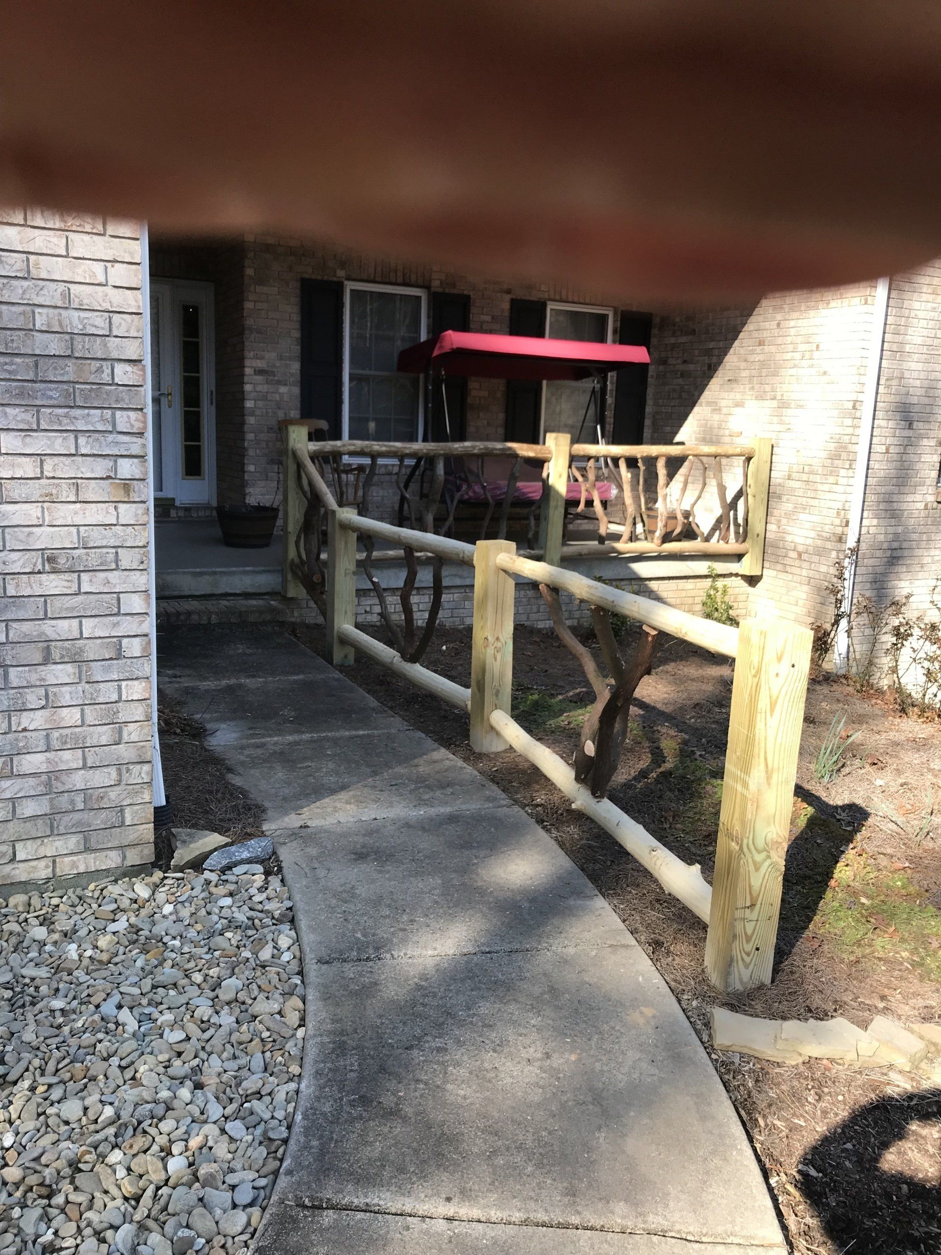 A wooden fence surrounds a walkway leading to a porch.