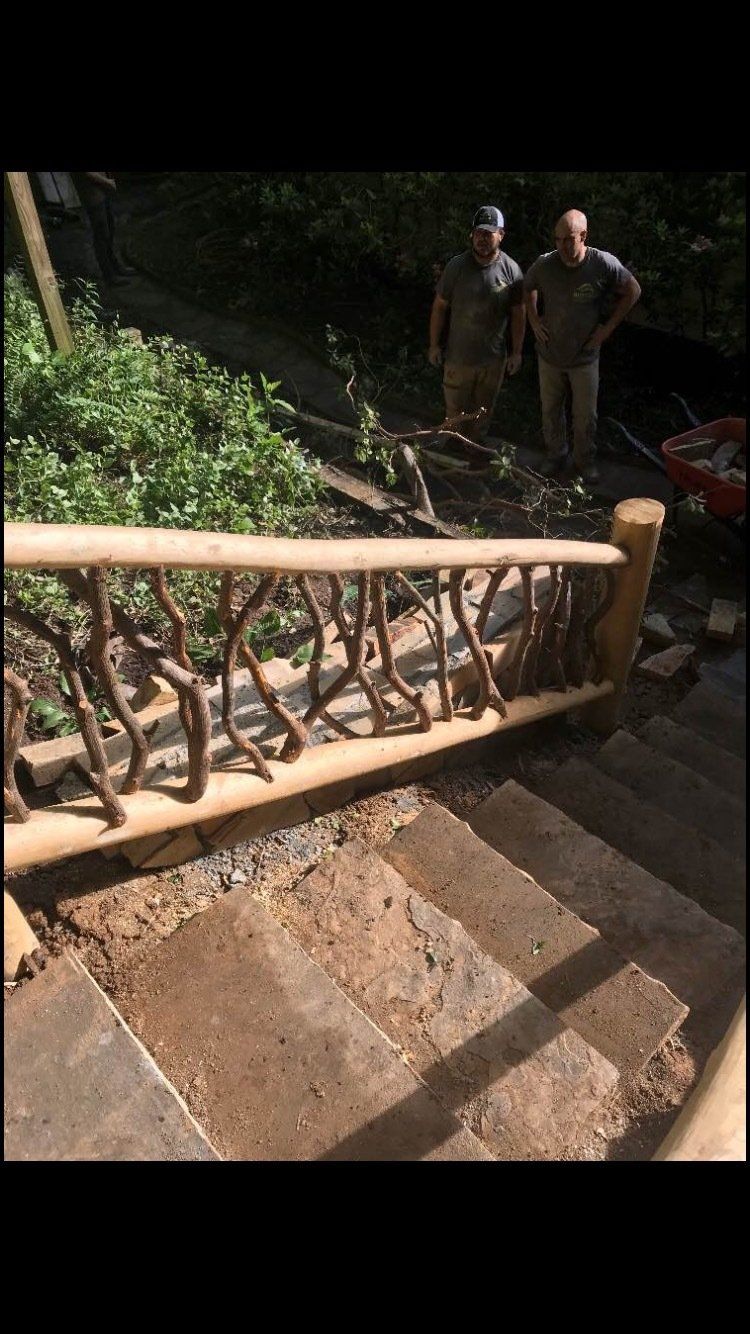 Two men are standing next to a wooden railing on a set of stairs.
