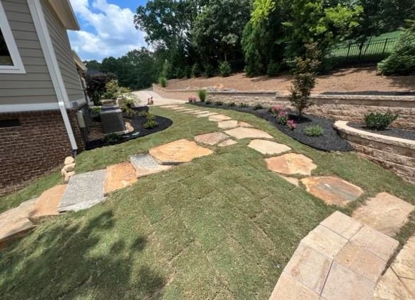 A stone walkway leading to a house in a backyard.