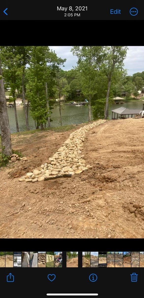 A phone screen shows a picture of a dirt field next to a lake.
