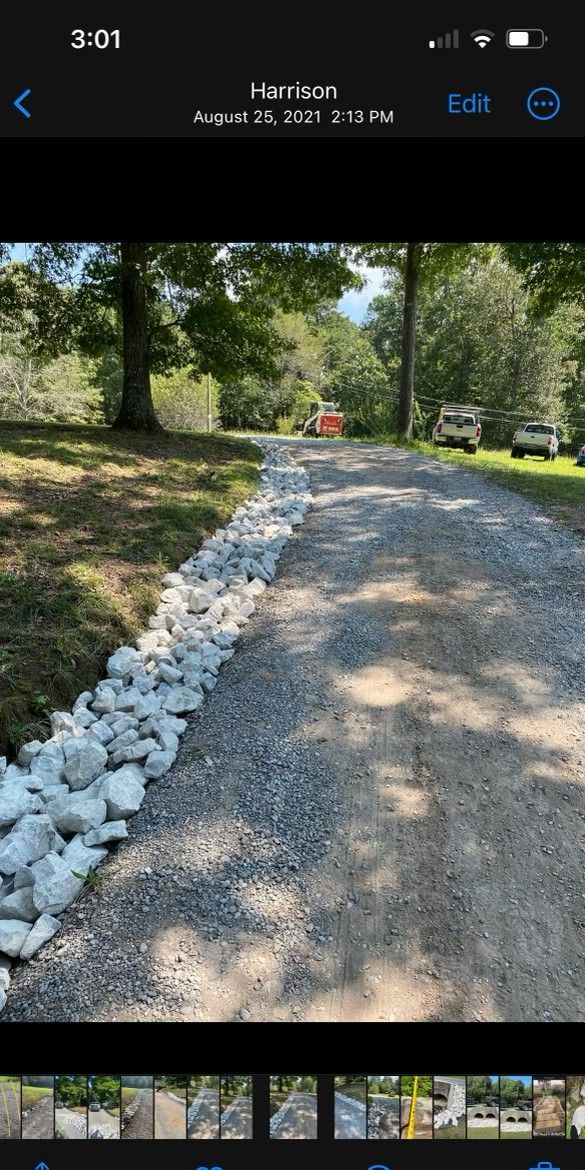 A picture of a gravel driveway with rocks on the side of it.