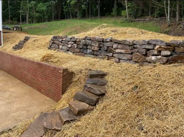 A pile of hay is sitting next to a pile of rocks.