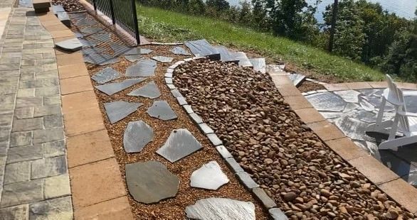A brick walkway with rocks and mulch on the side of it.