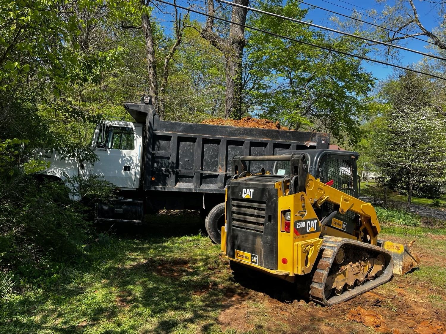 A dump truck and a bulldozer are parked in a dirt field.