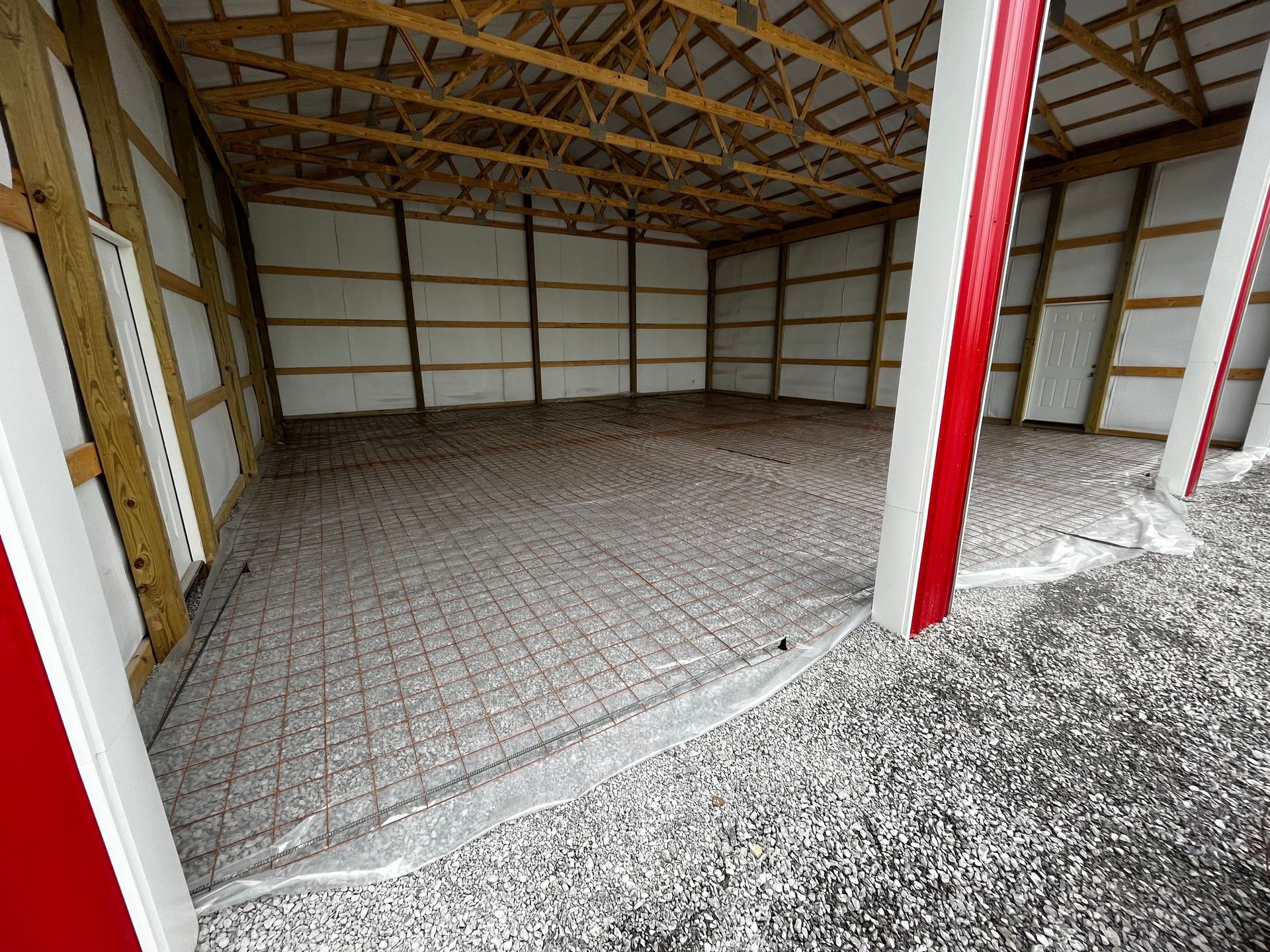 A large empty barn with a lot of gravel on the floor.
