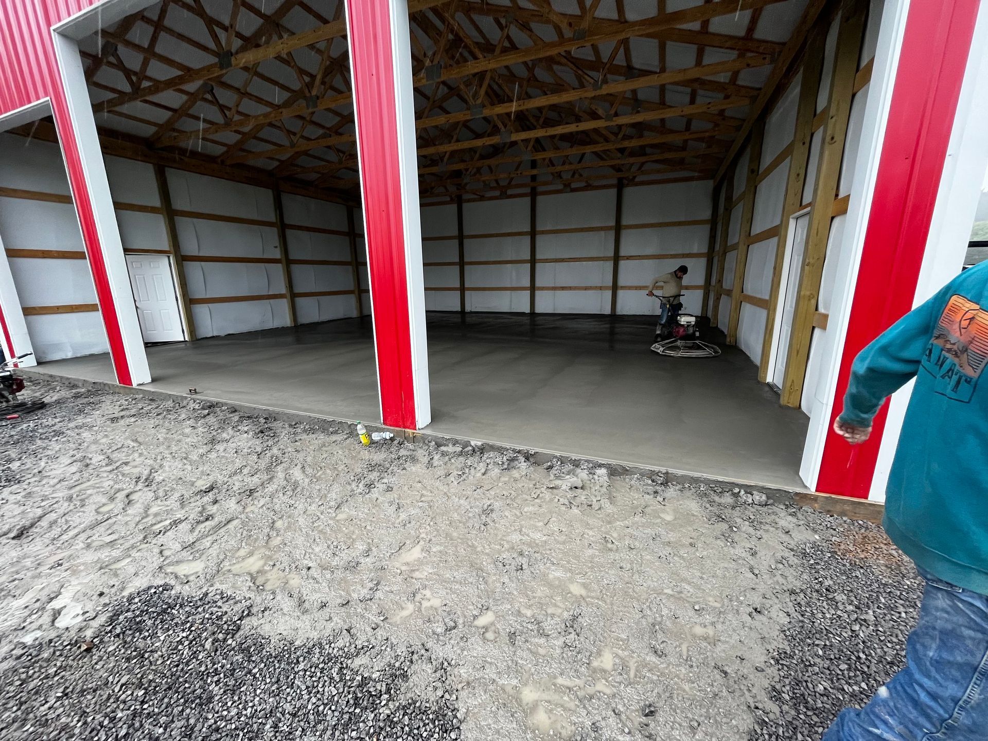 A man is working on a concrete floor inside of a barn.