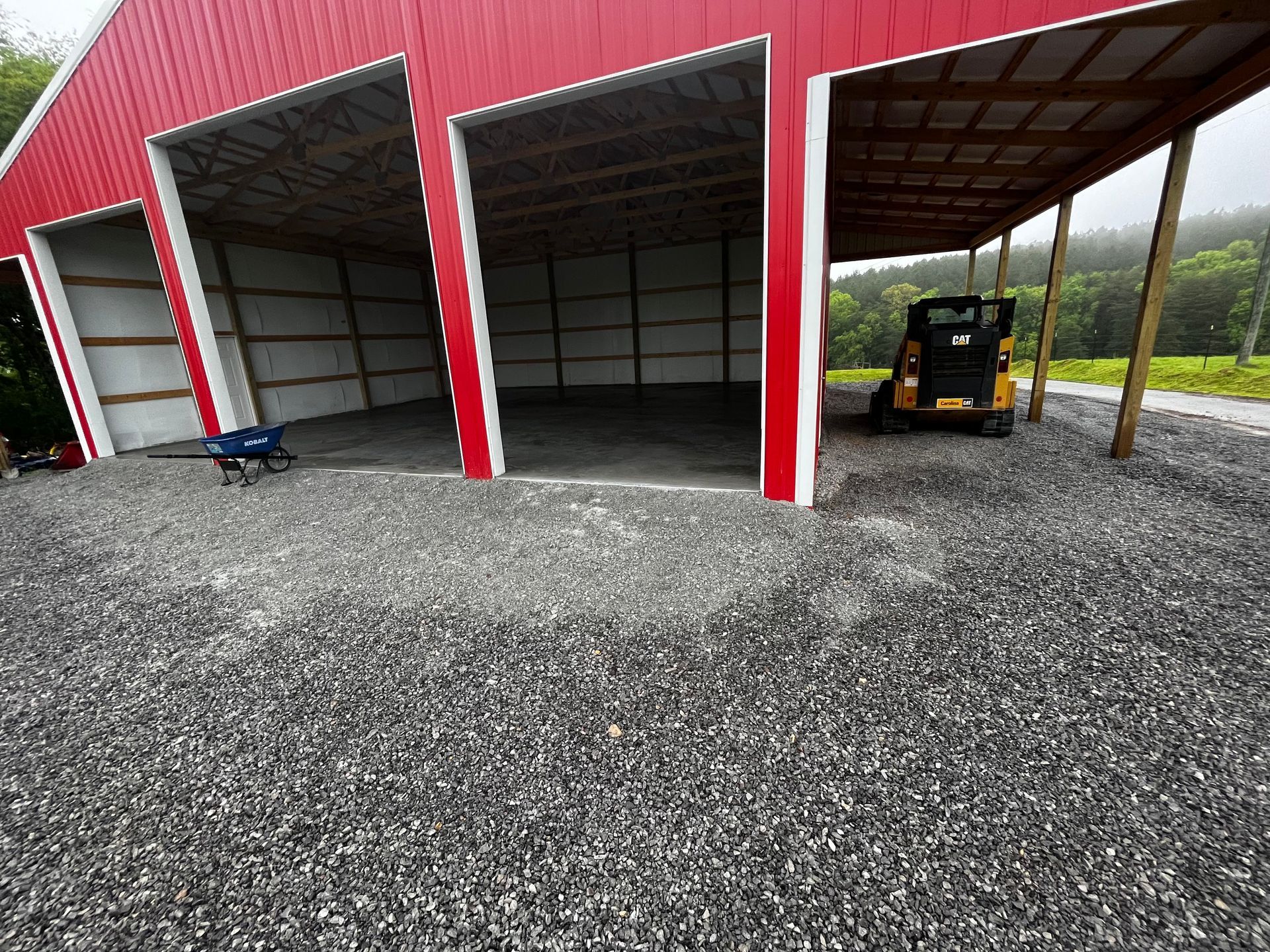 A yellow forklift is parked under a red barn.