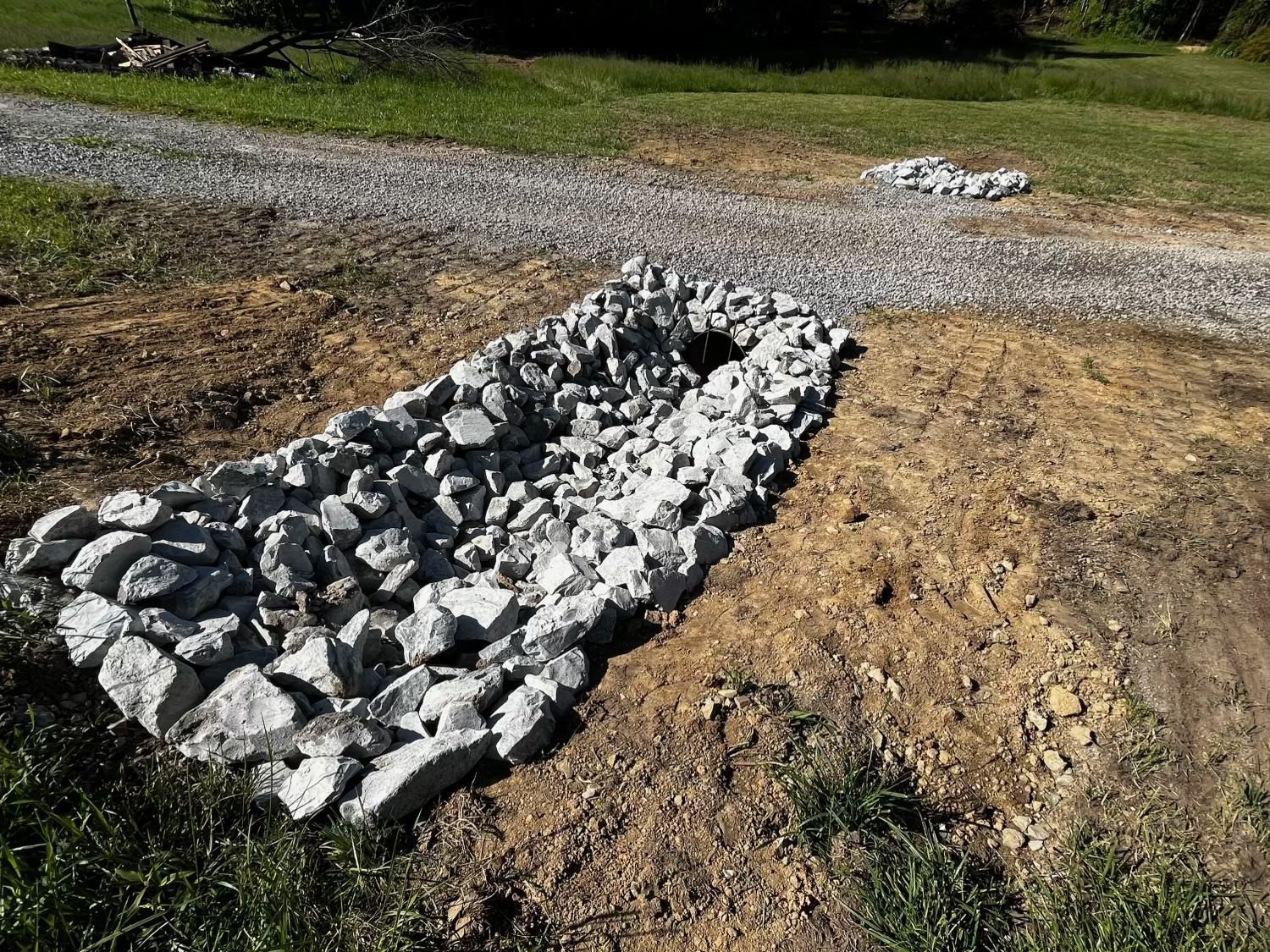 A pile of rocks is sitting in the dirt next to a gravel road.