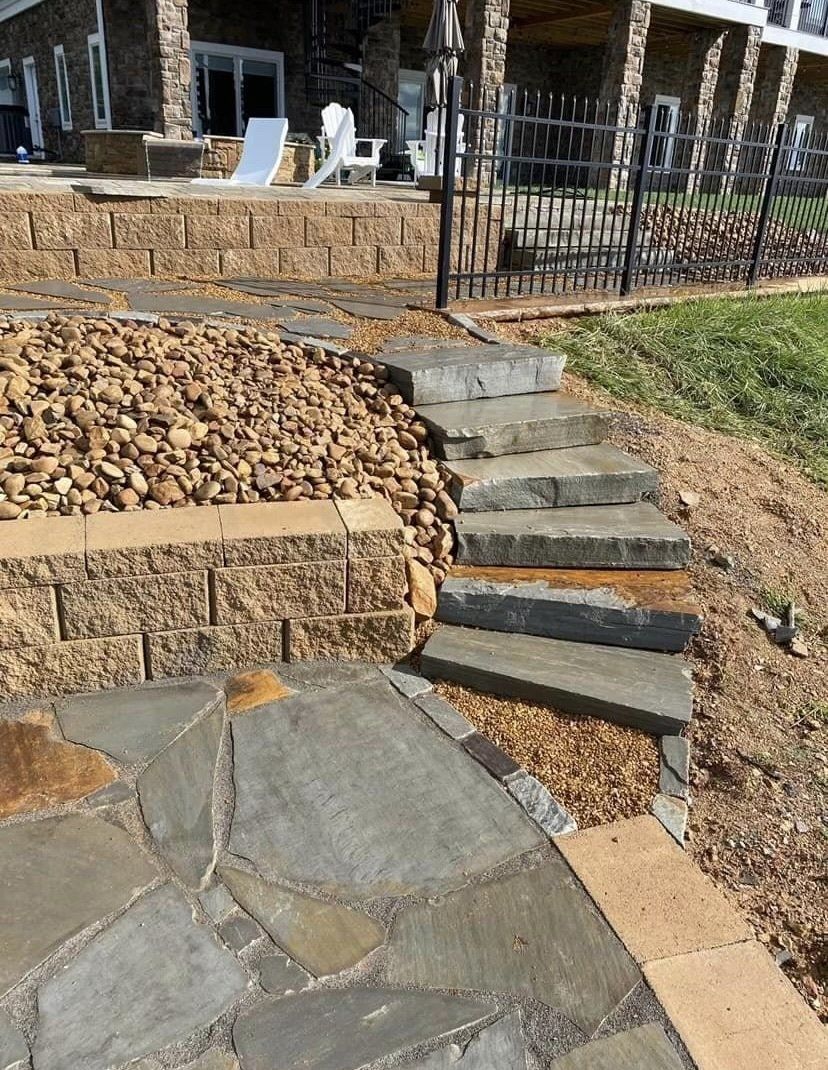 A stone walkway leading to a house with stairs leading up to it.