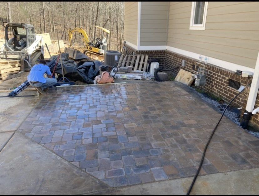 A man is working on a patio in front of a house.