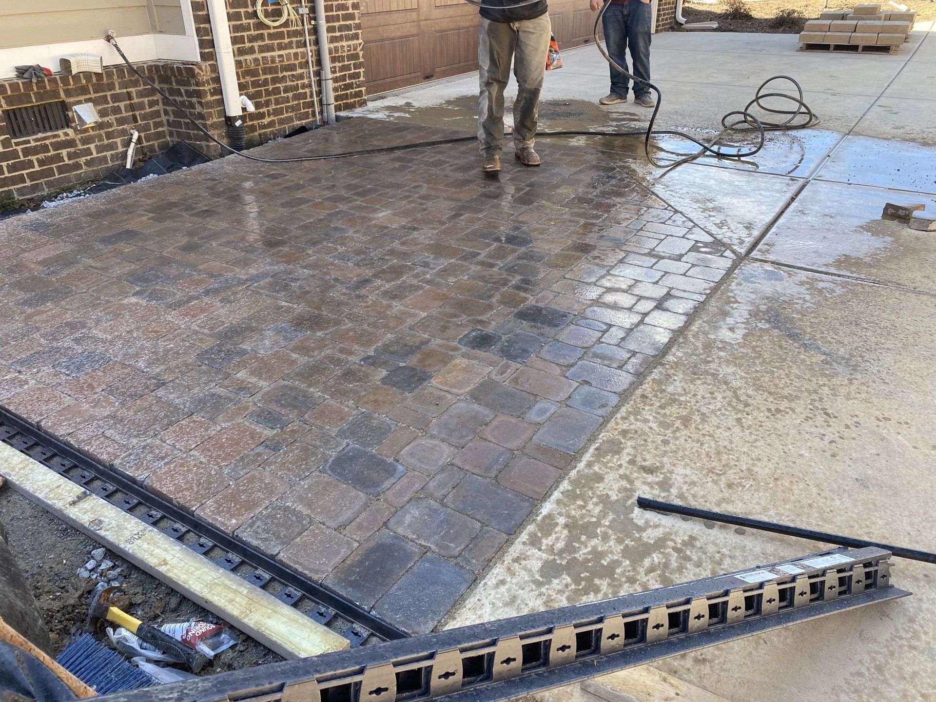 A man is standing on a brick driveway next to a ladder.