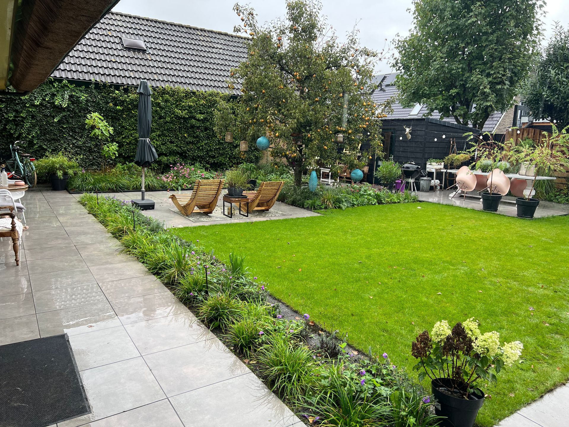 Een groot gazon met een terras en stoelen