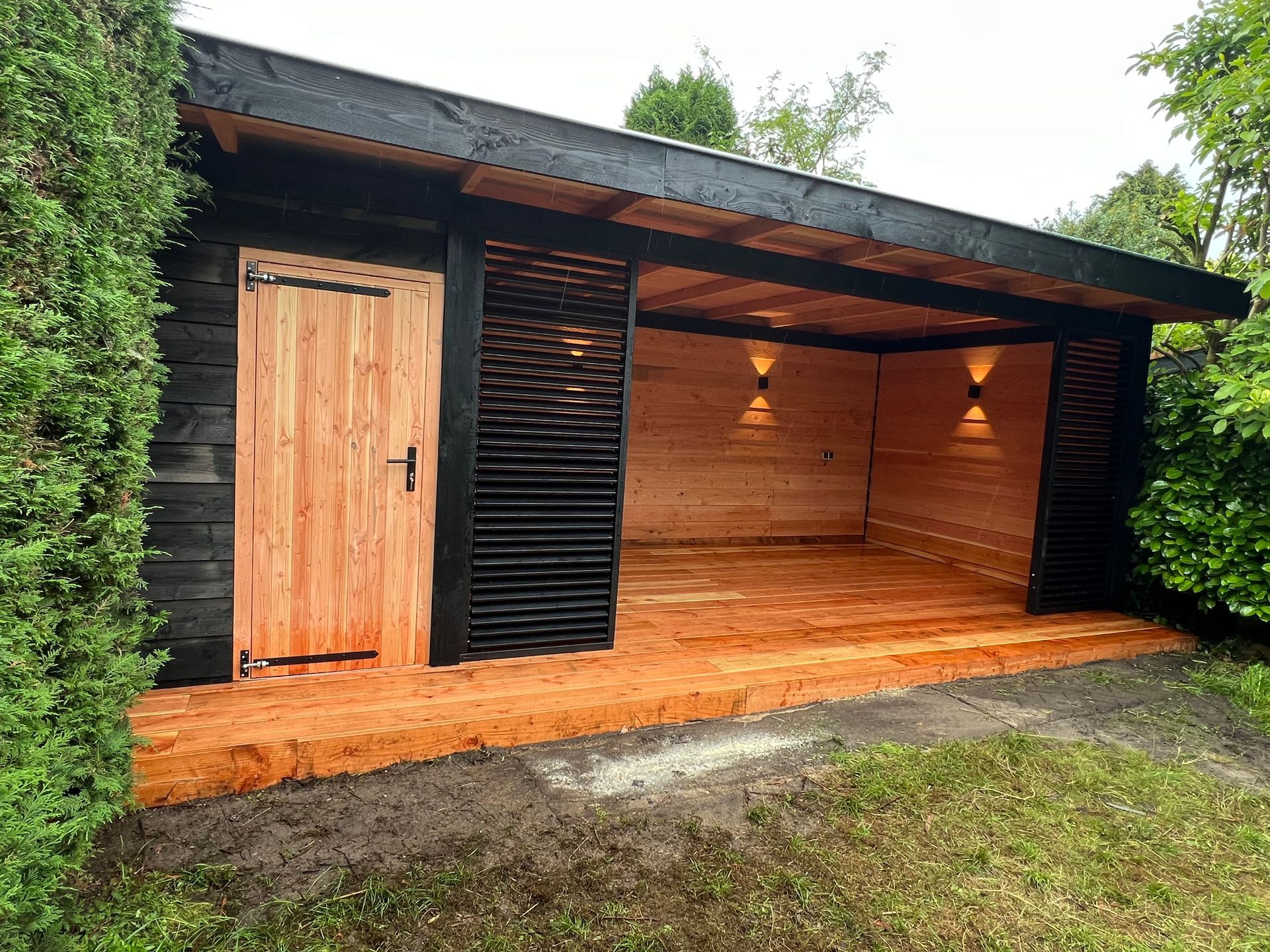 Een houten schuur met een houten terras en een houten deur.