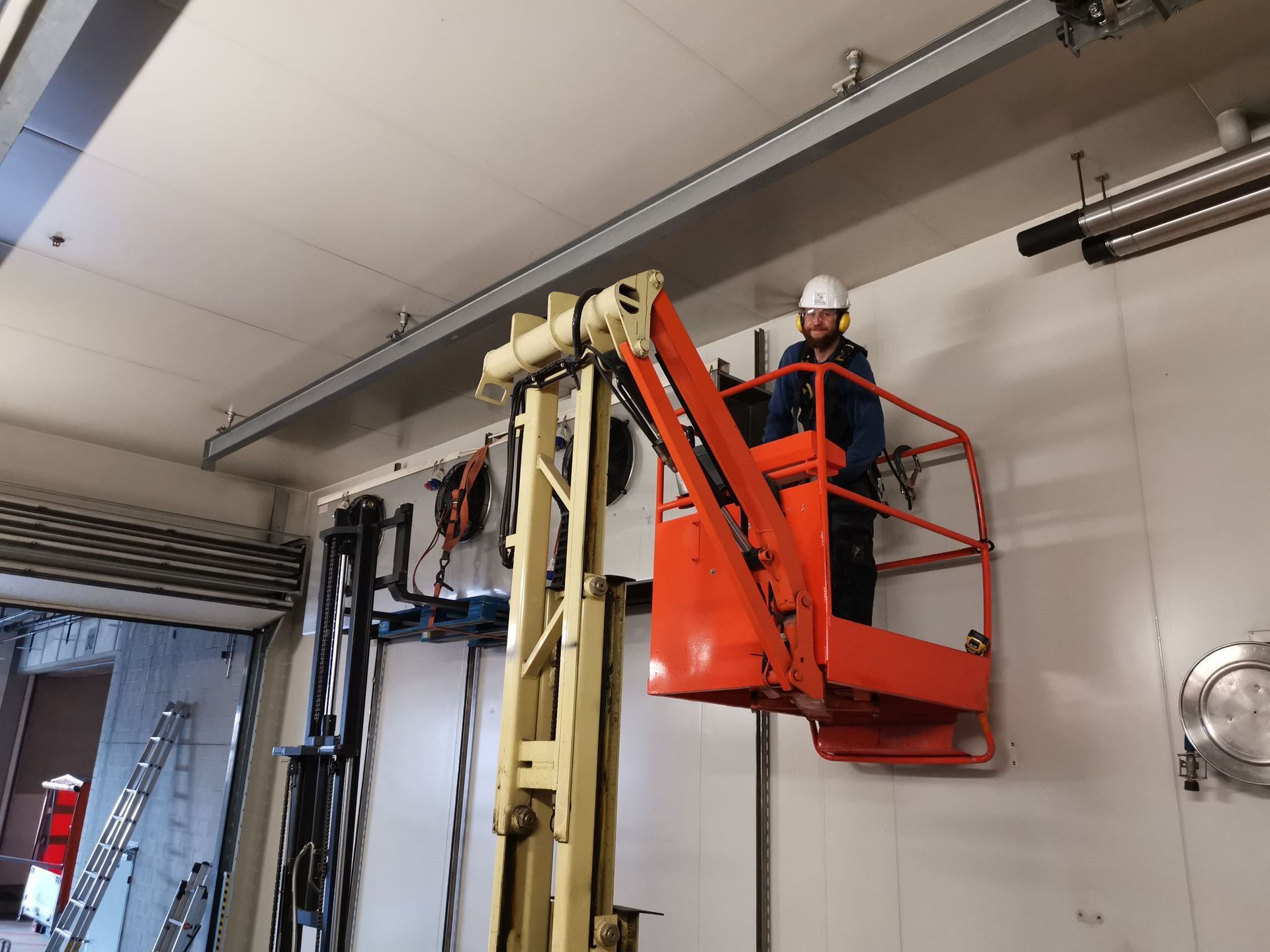 Ein Mann steht in einer Lagerhalle auf einem Gabelstapler.