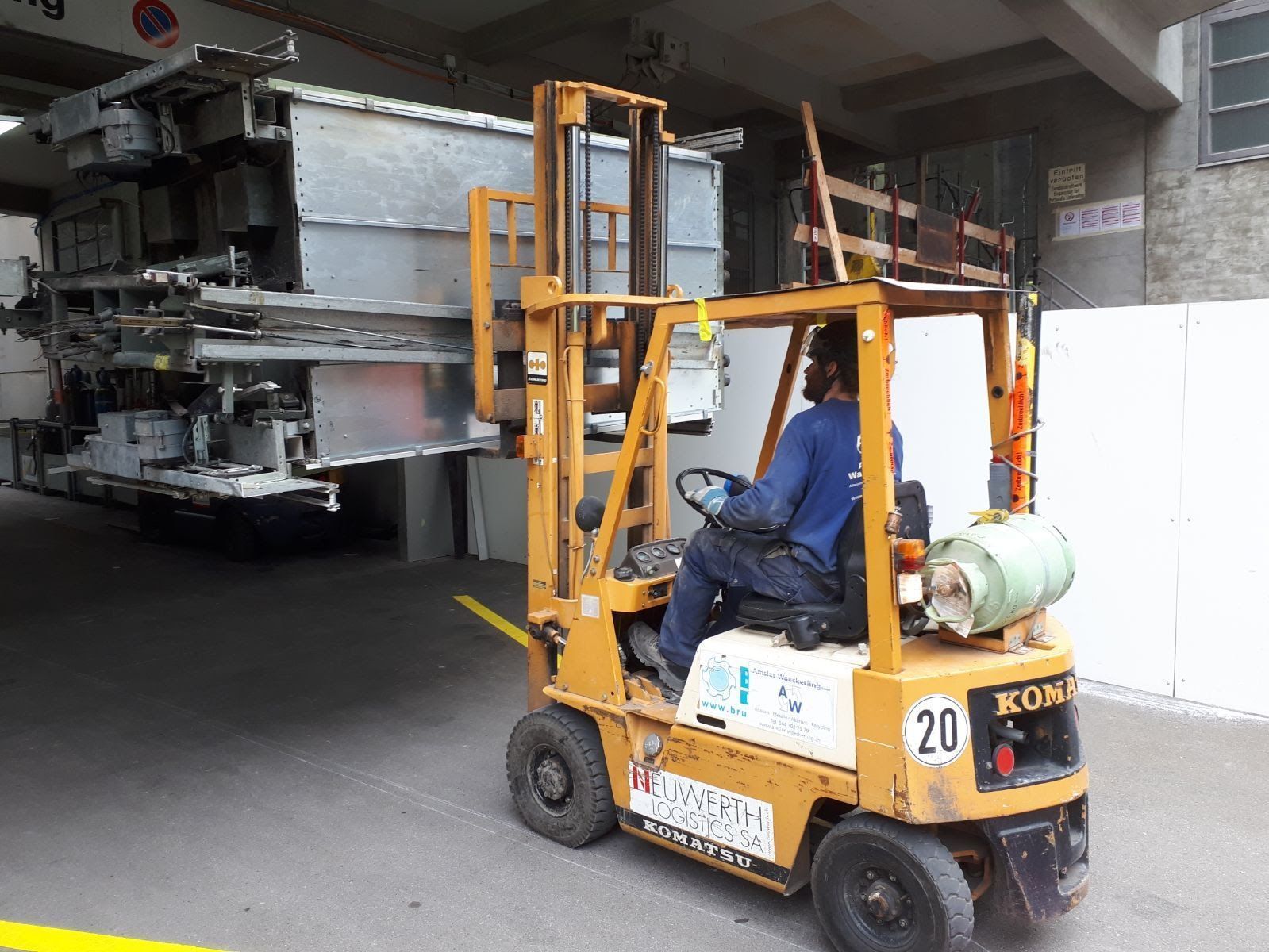 Ein Mann fährt einen Gabelstapler auf einem Parkplatz.