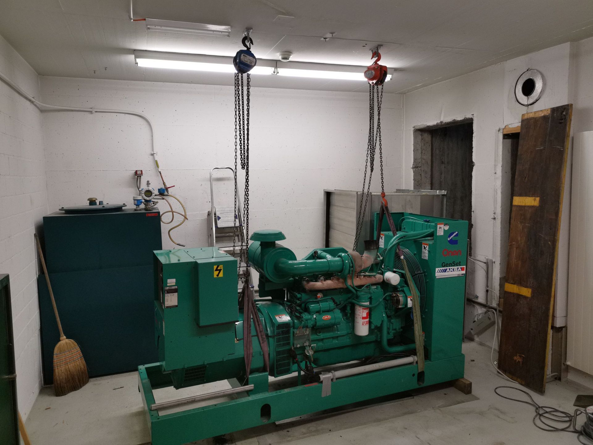 Ein grüner Generator wird von einem Kran in einen Raum gehoben.