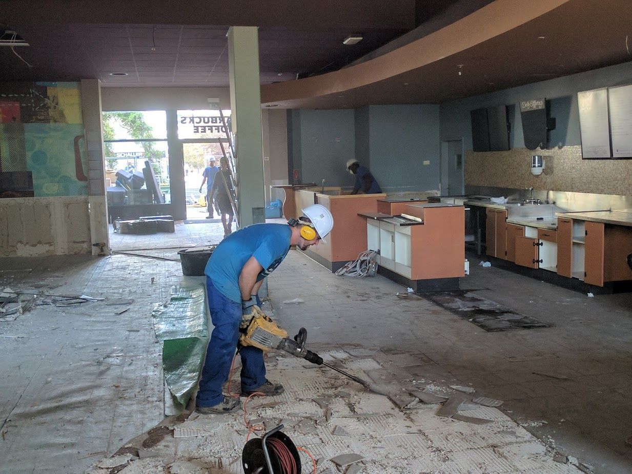 Ein Mann in einem blauen Hemd benutzt einen Hammer in einem leeren Raum