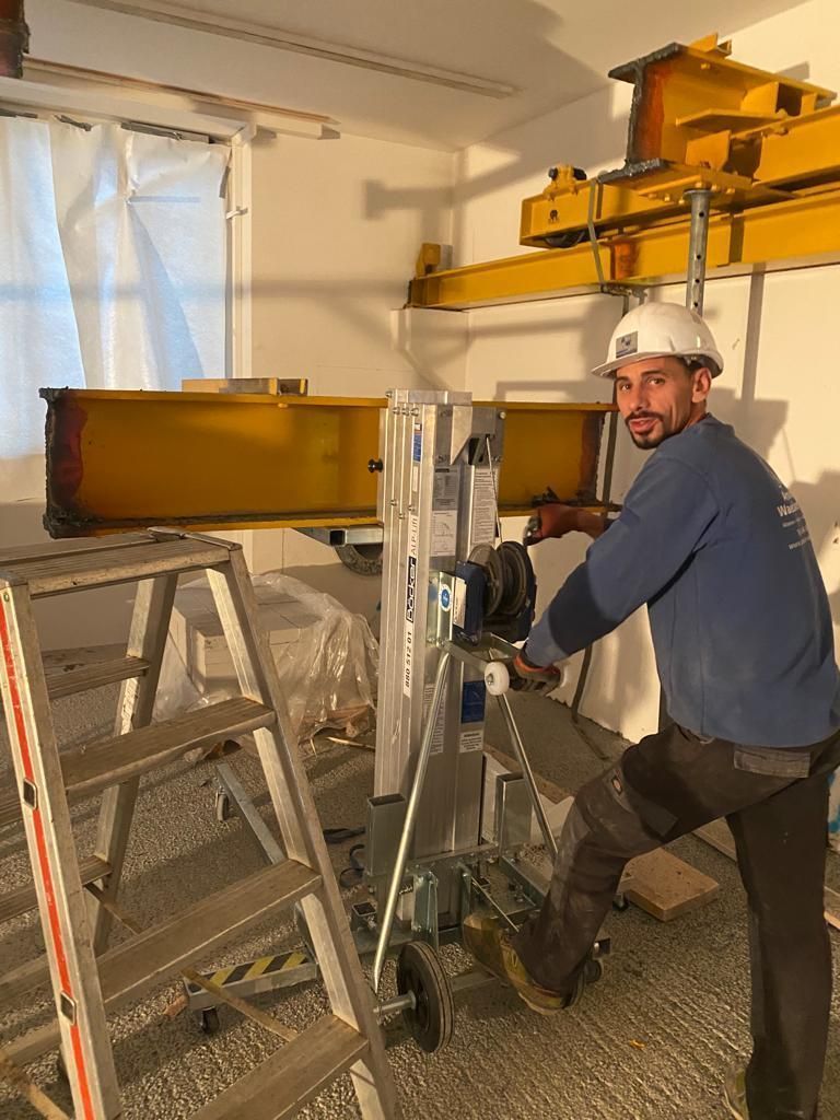 Ein Mann steht neben einer Leiter in einem Raum.