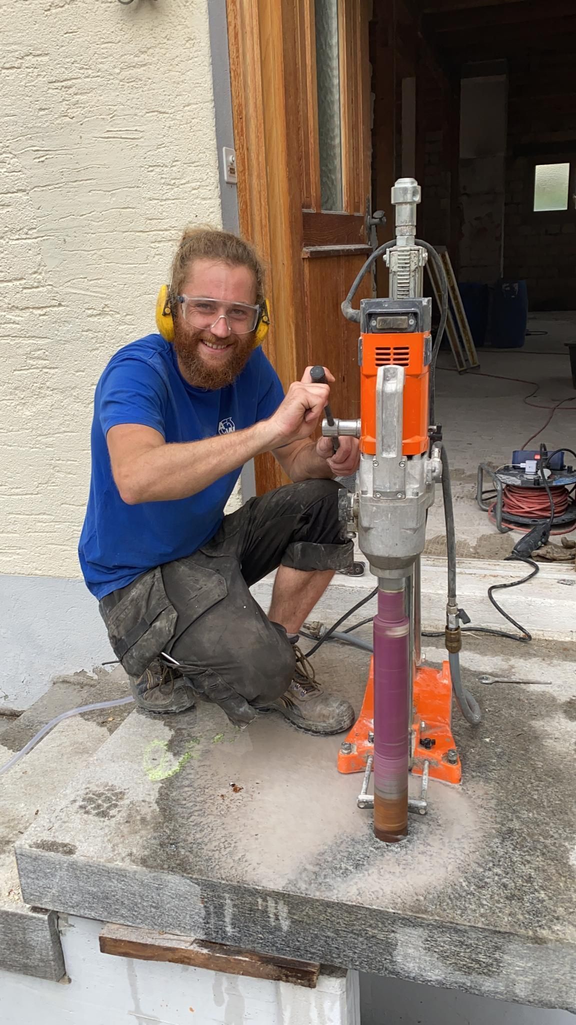 Ein Mann kniet neben einer Maschine.