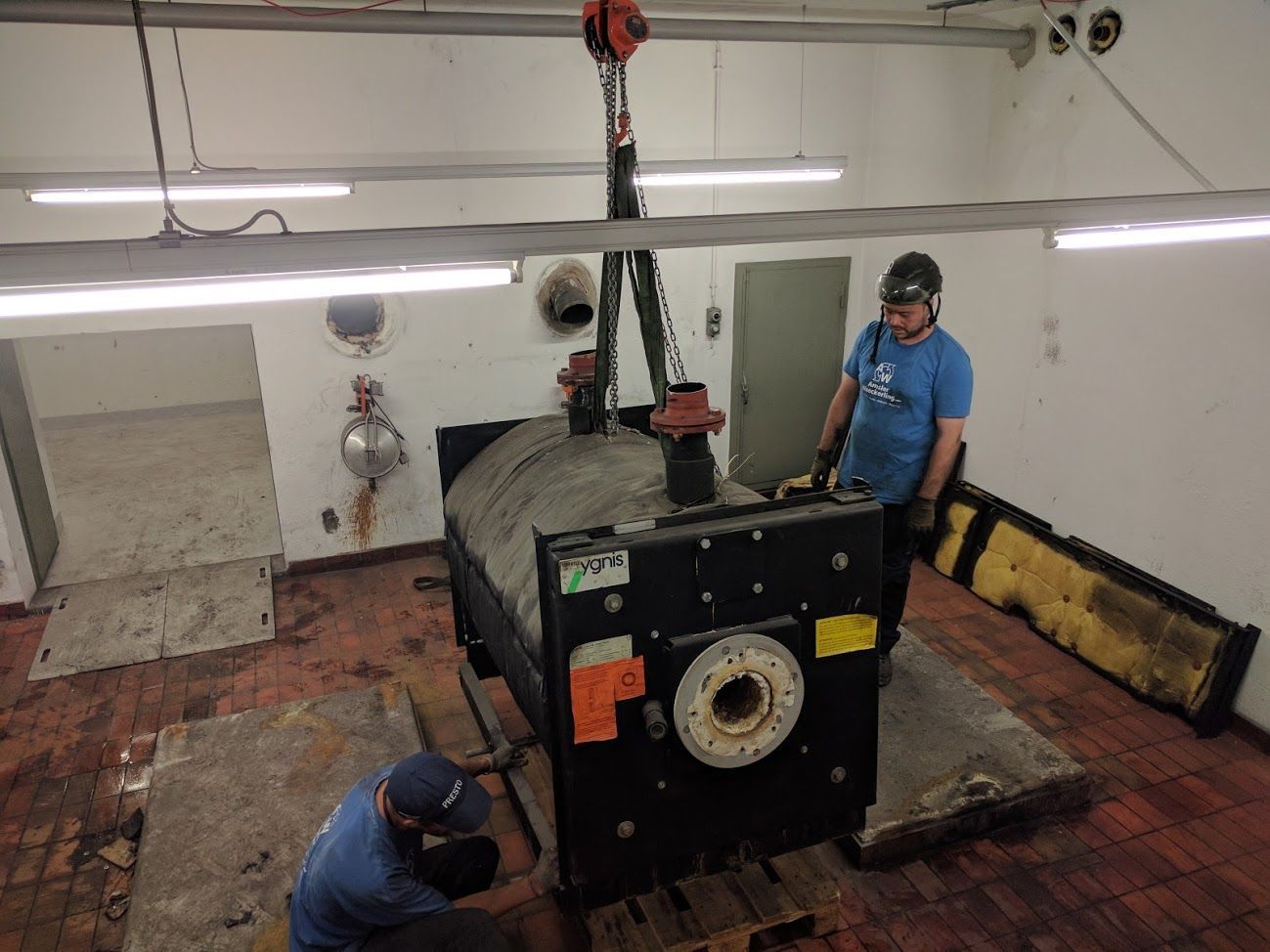 Zwei Männer arbeiten in einem Raum an einer großen Maschine.