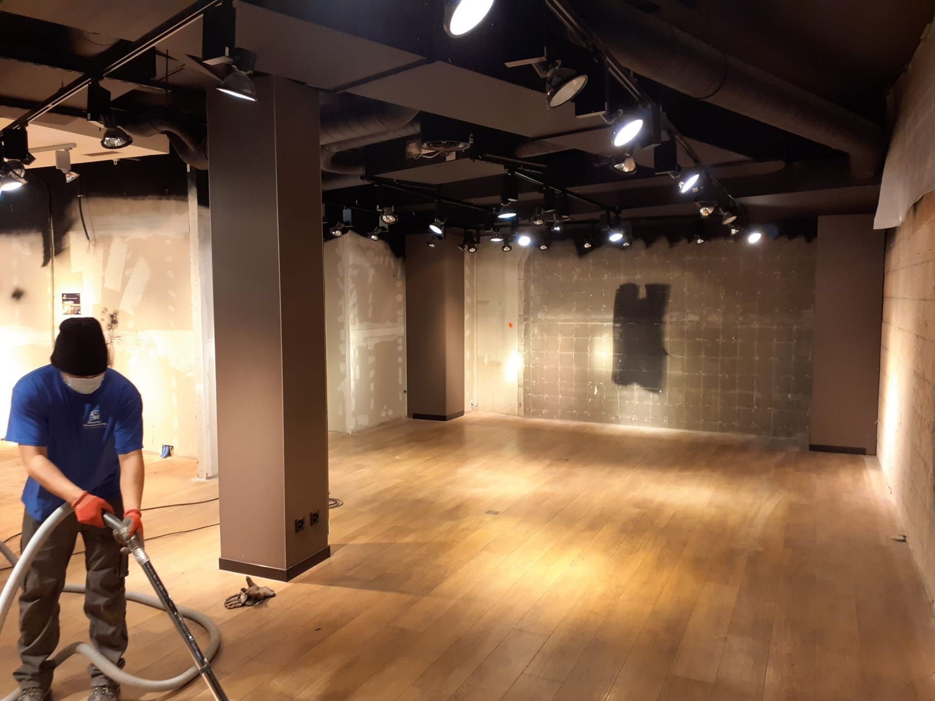 Ein Mann reinigt einen großen leeren Raum mit einem Staubsauger.