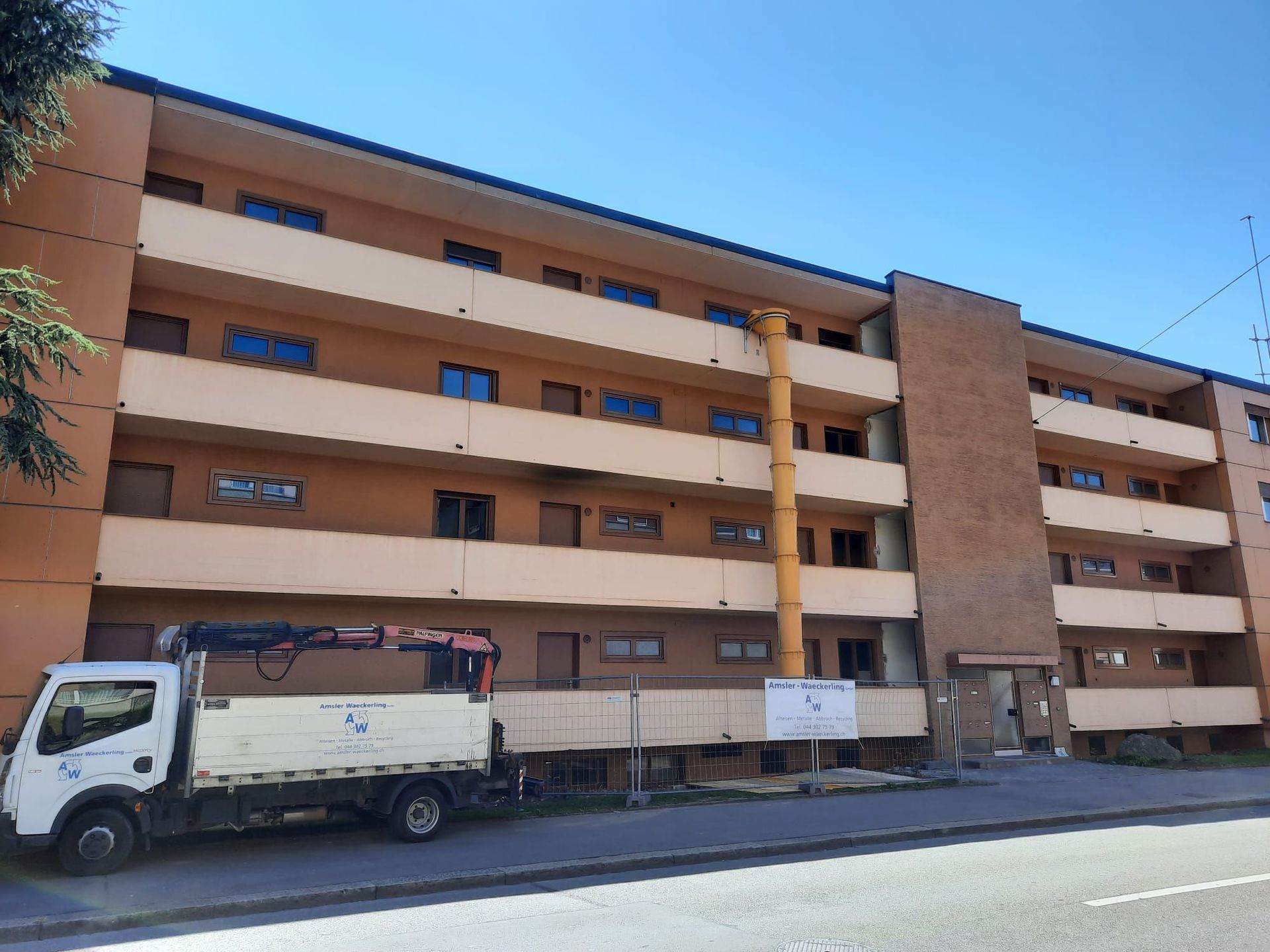 Ein weißer Lastwagen steht vor einem großen Wohnhaus