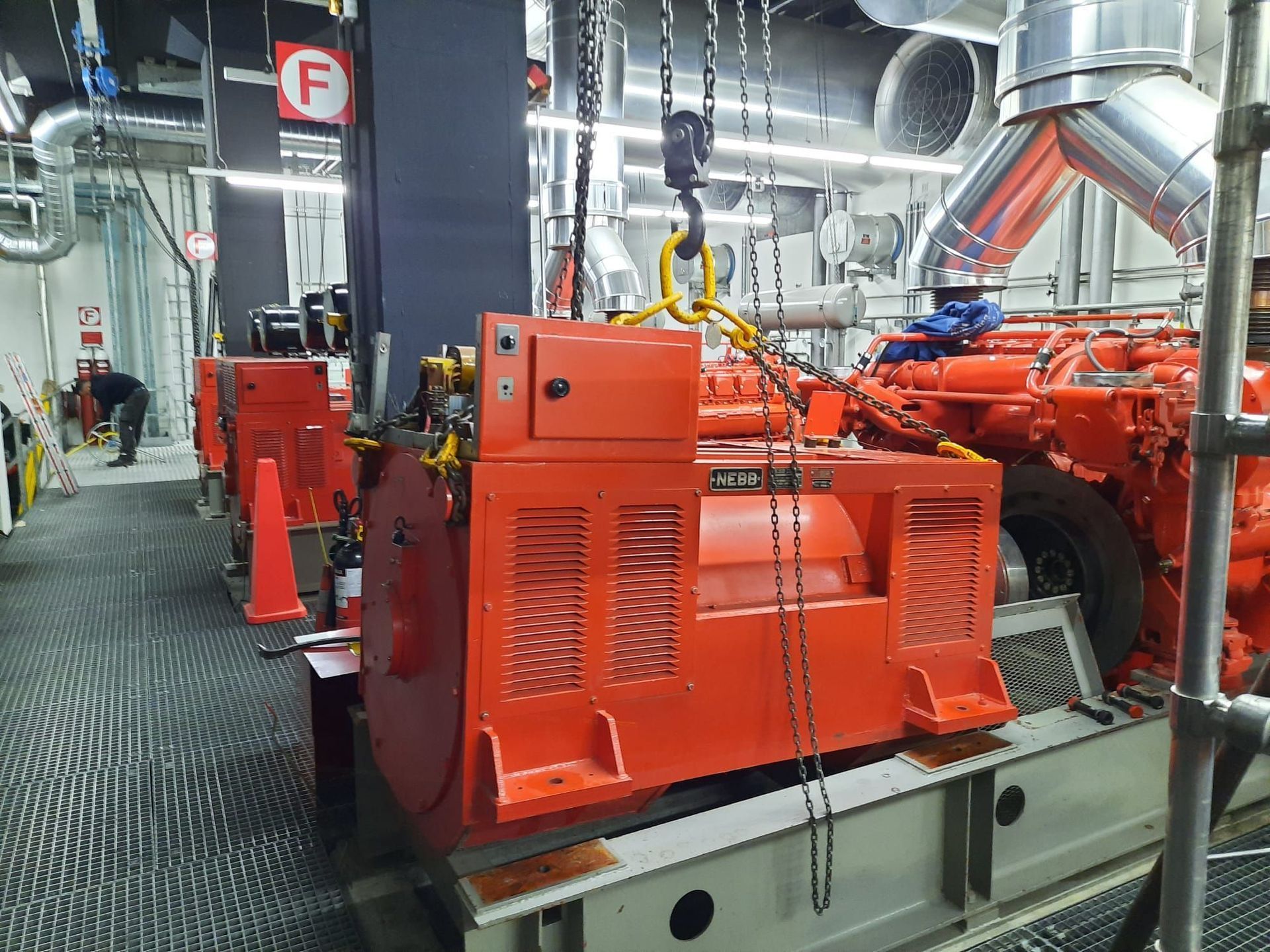 In einer Fabrik wird eine große rote Lokomotive von einem Kran angehoben.