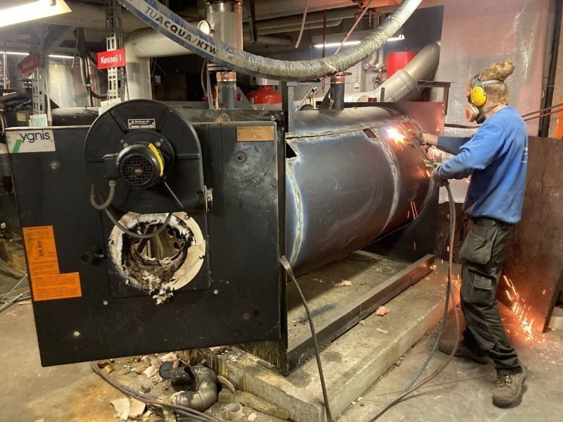 Ein Mann schweißt in einer Fabrik ein großes Metallobjekt.