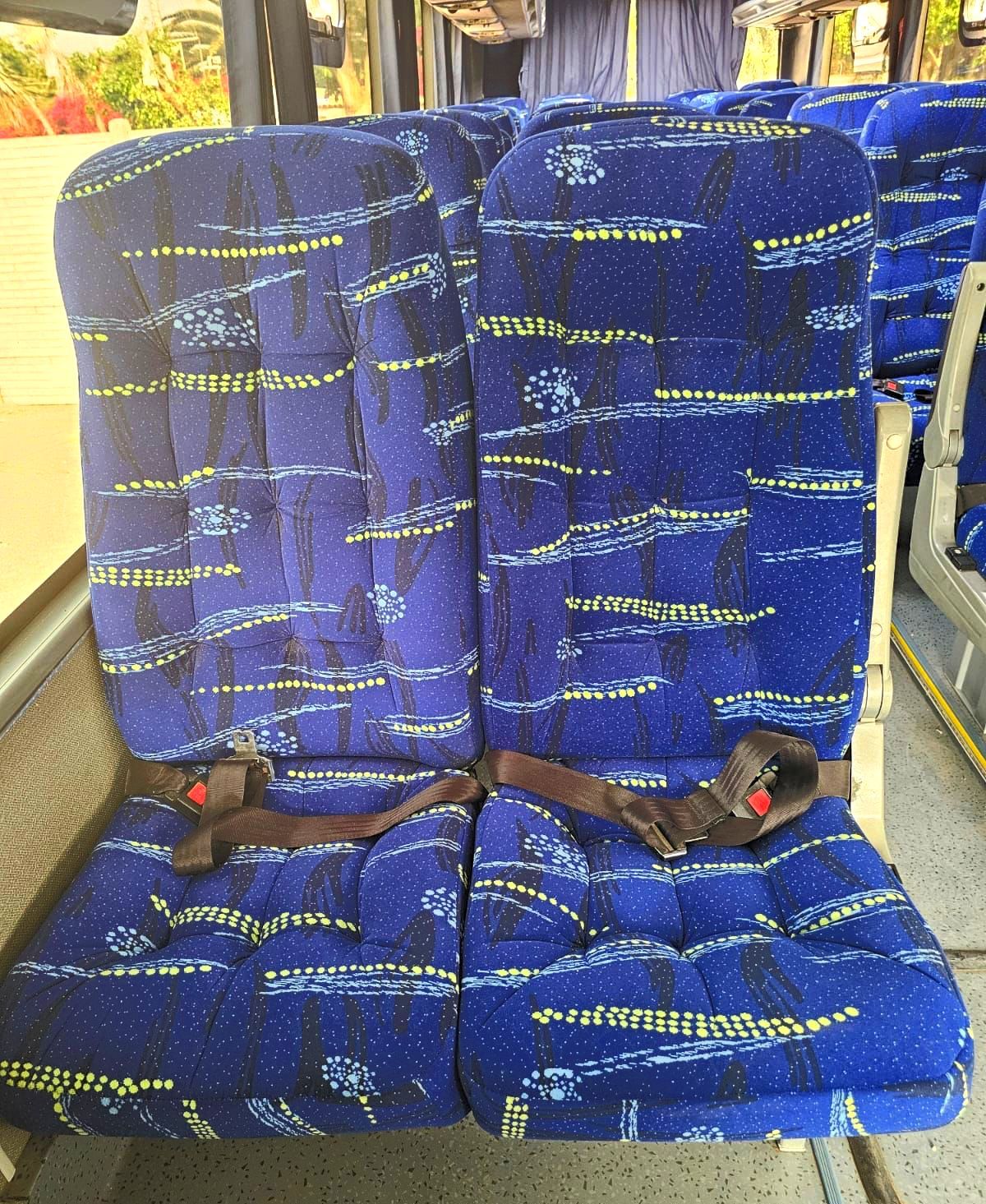 Dos asientos azules en un autobús con cinturones de seguridad.