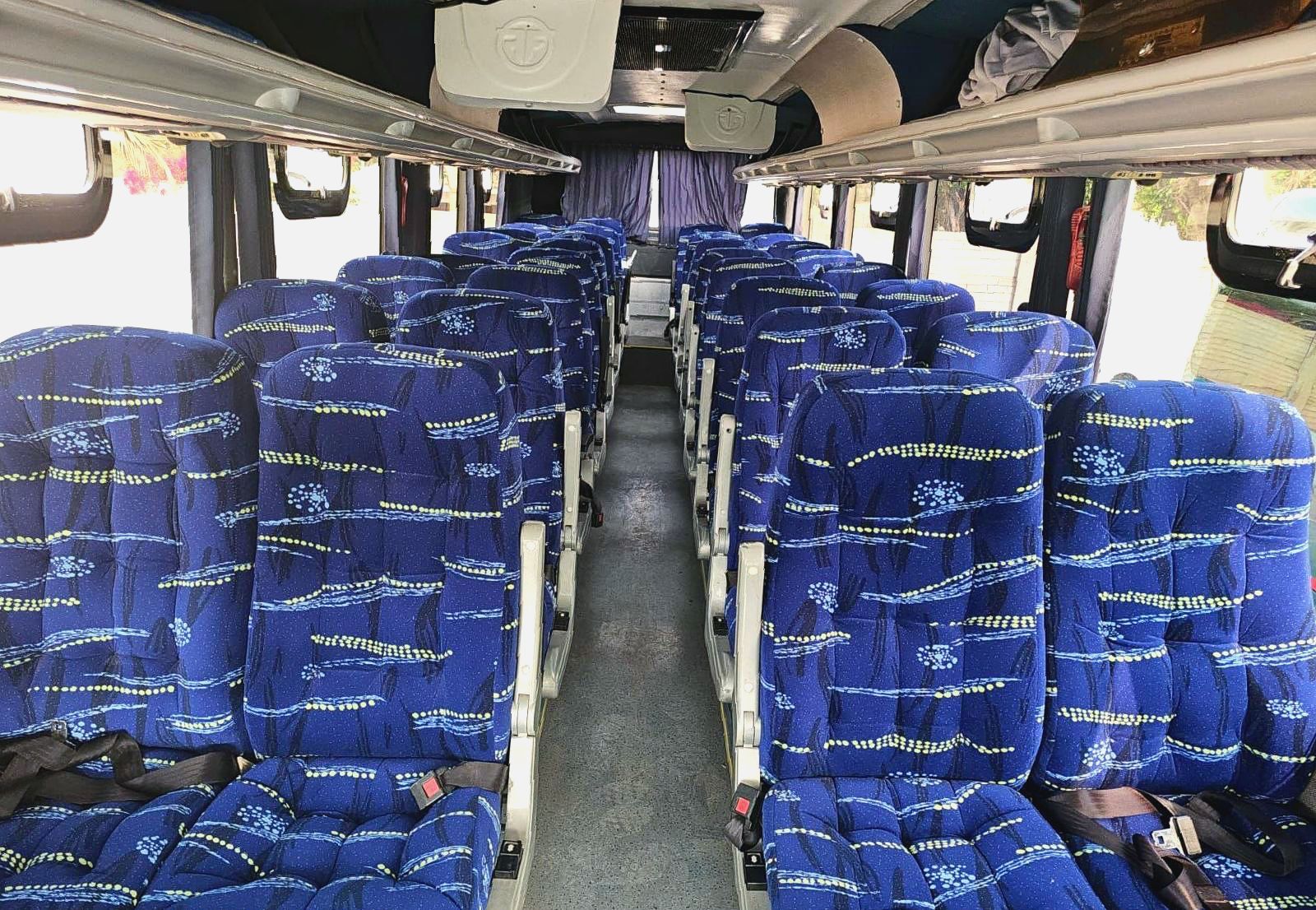 El interior de un autobús con muchos asientos azules.