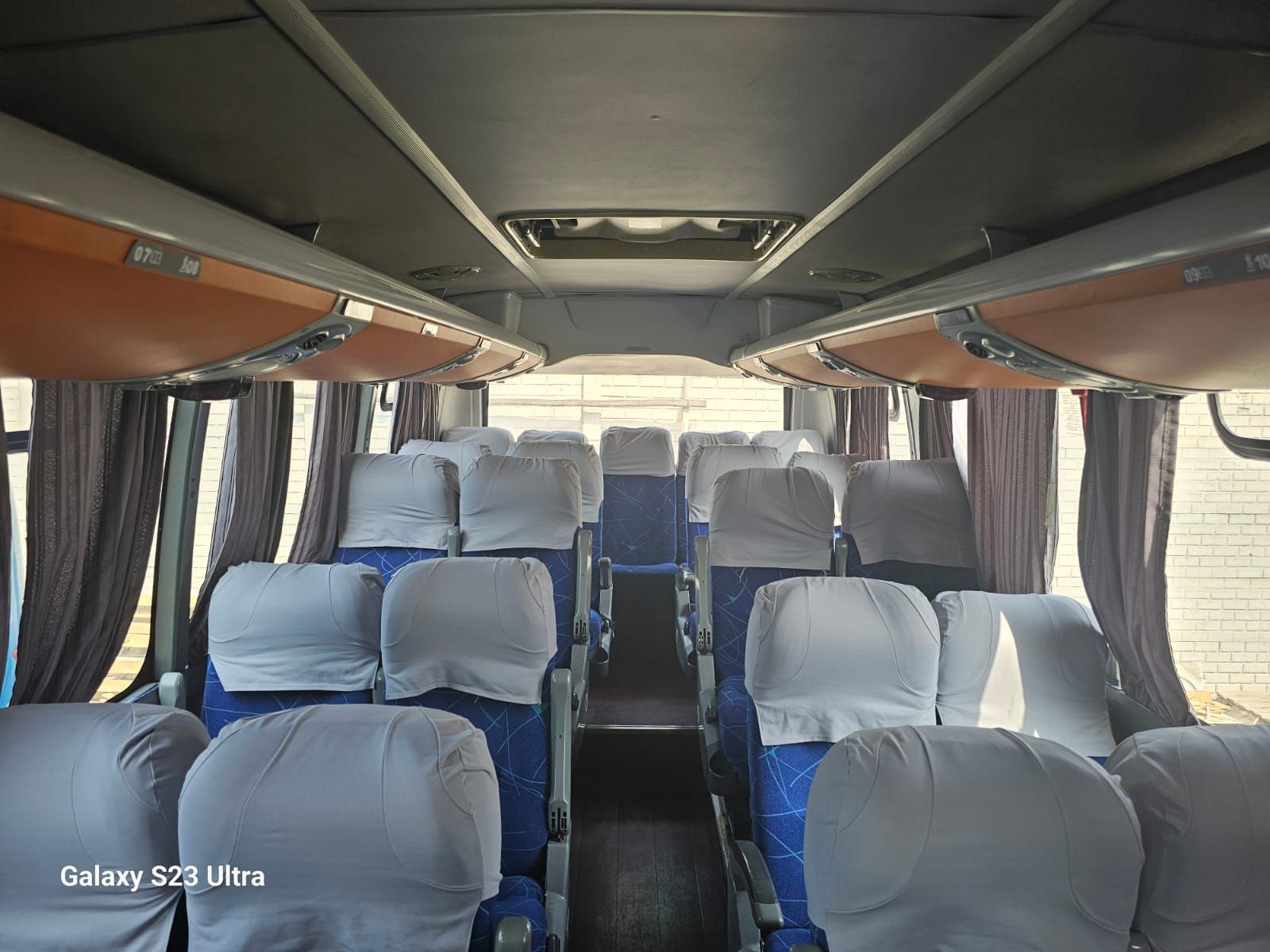 El interior de un autobús con asientos azules y blancos.